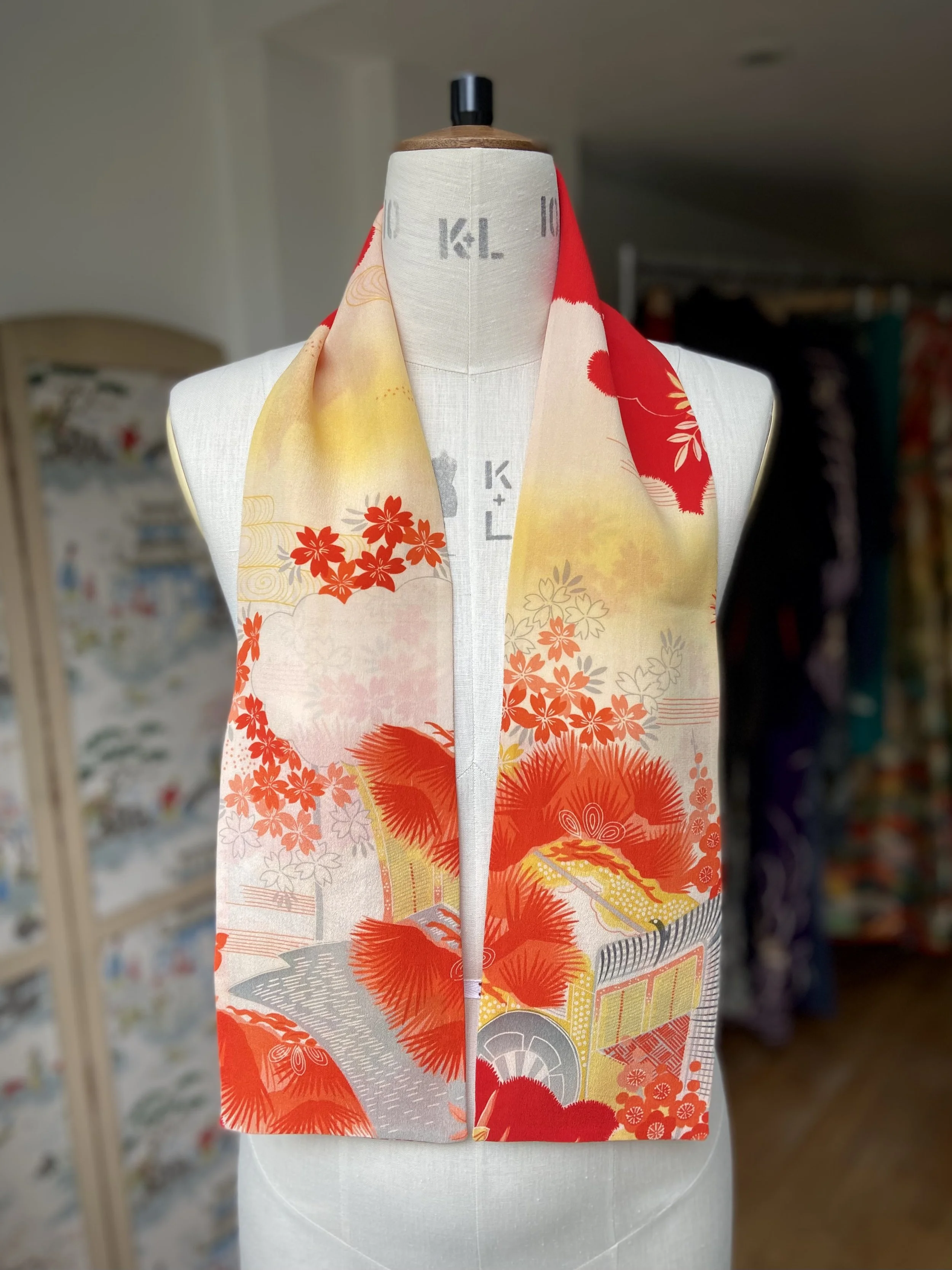 Bright vermillion red and yellow scarf presented on a dress stand, with printed blossom design, handmade from repurposed Japanese kimono crepe silk by Kirsty Chivers