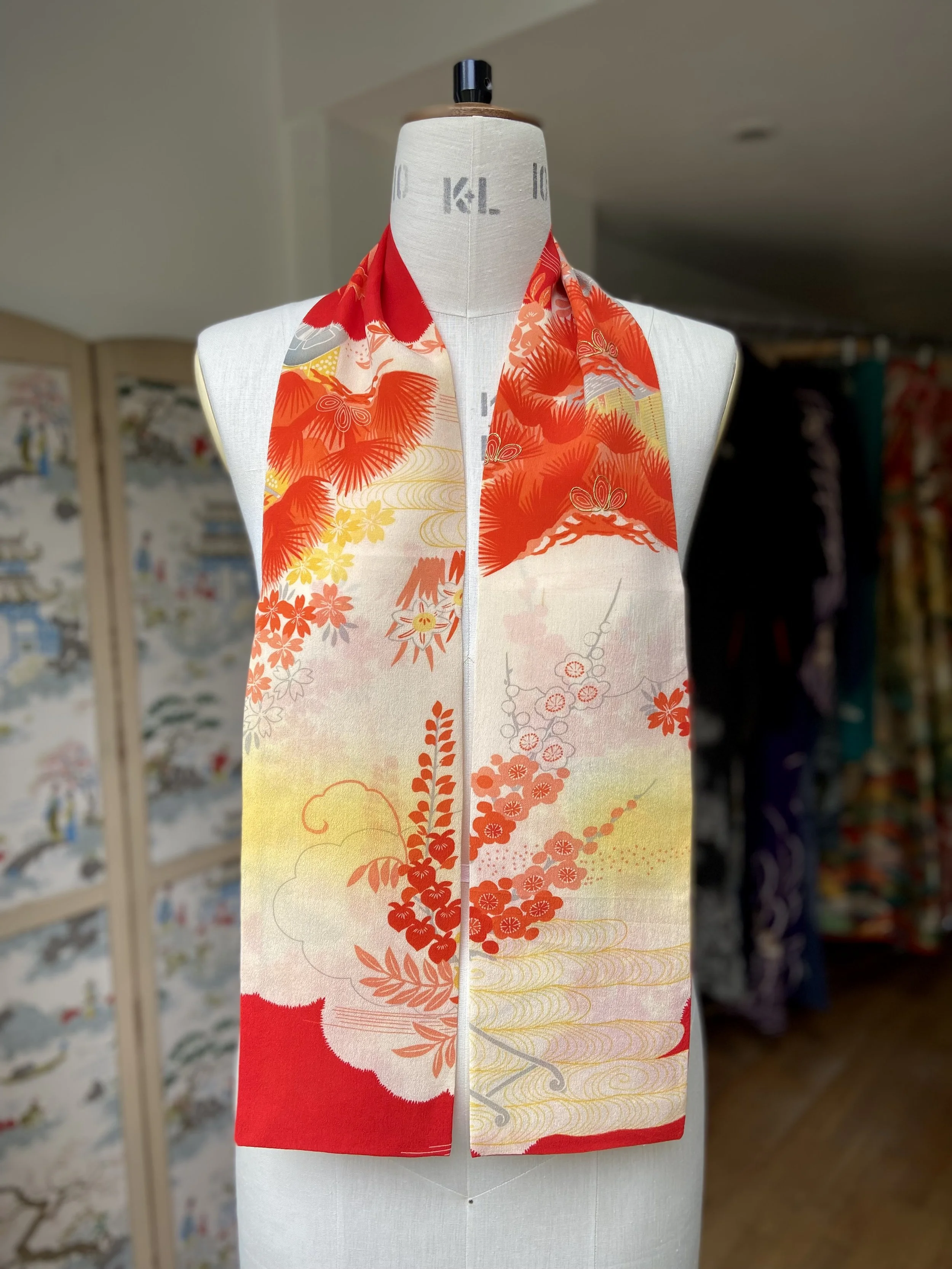Bright vermillion red and yellow scarf presented on a dress stand, with printed blossom design, handmade from repurposed Japanese kimono crepe silk by Kirsty Chivers