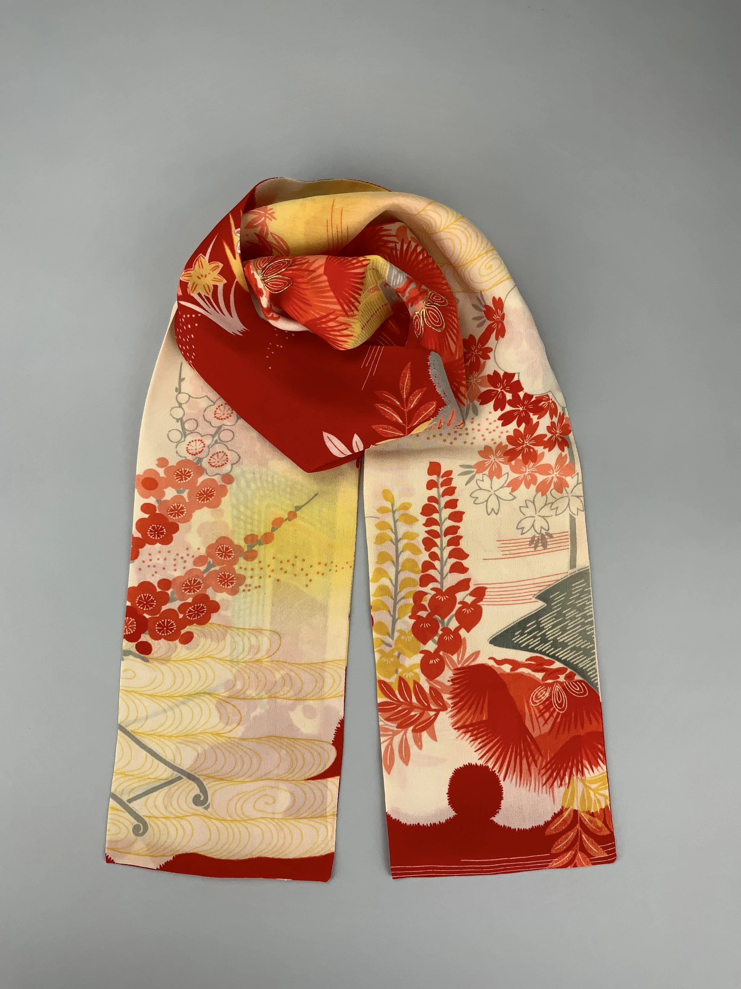 Flatlay of vibrant red and yellow scarf with printed blossom design, handmade from repurposed Japanese kimono crepe silk by Kirsty Chivers