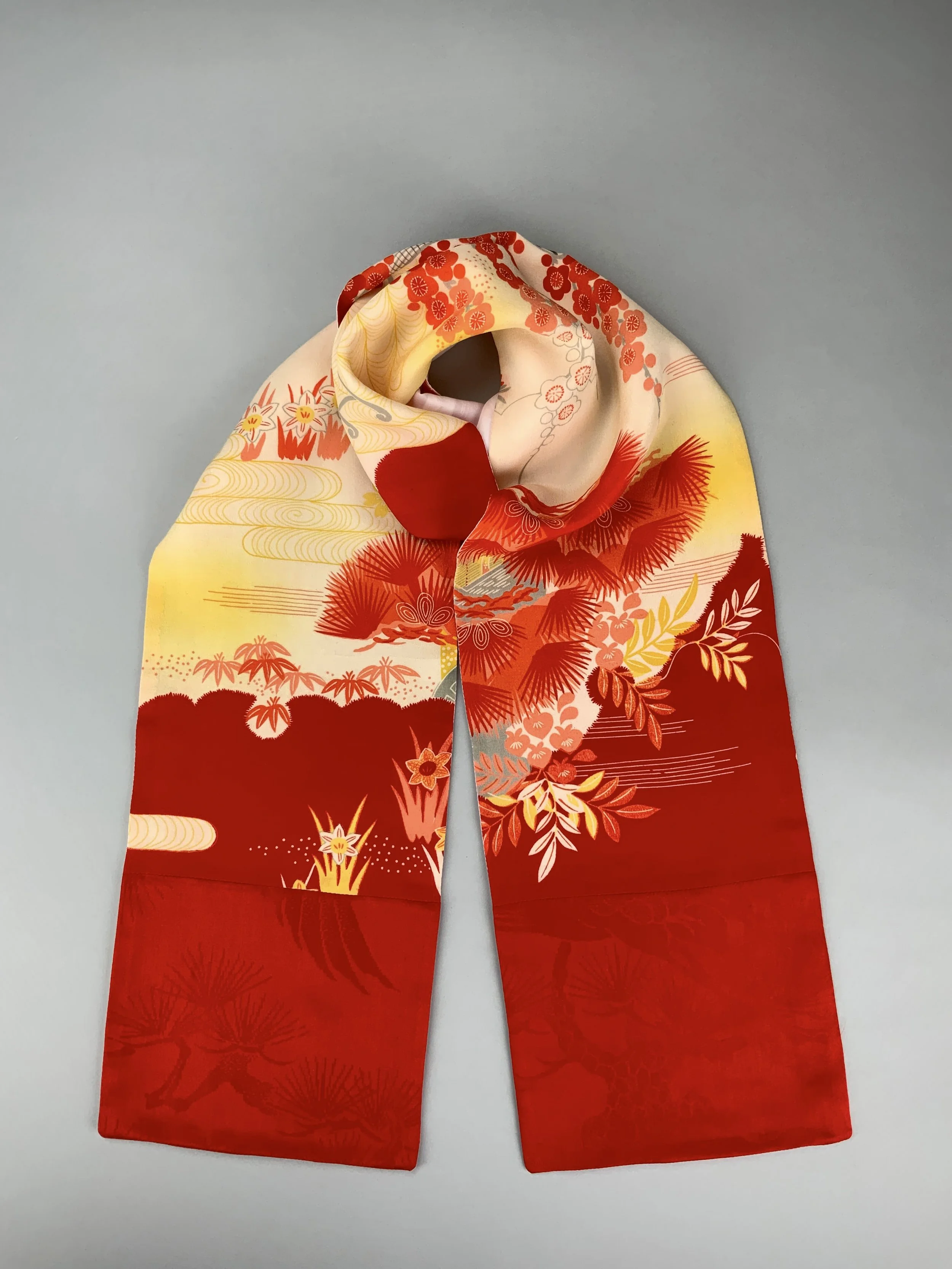 Flatlay showing vibrant red and yellow scarf with printed blossom design, handmade from repurposed Japanese kimono crepe silk by Kirsty Chivers