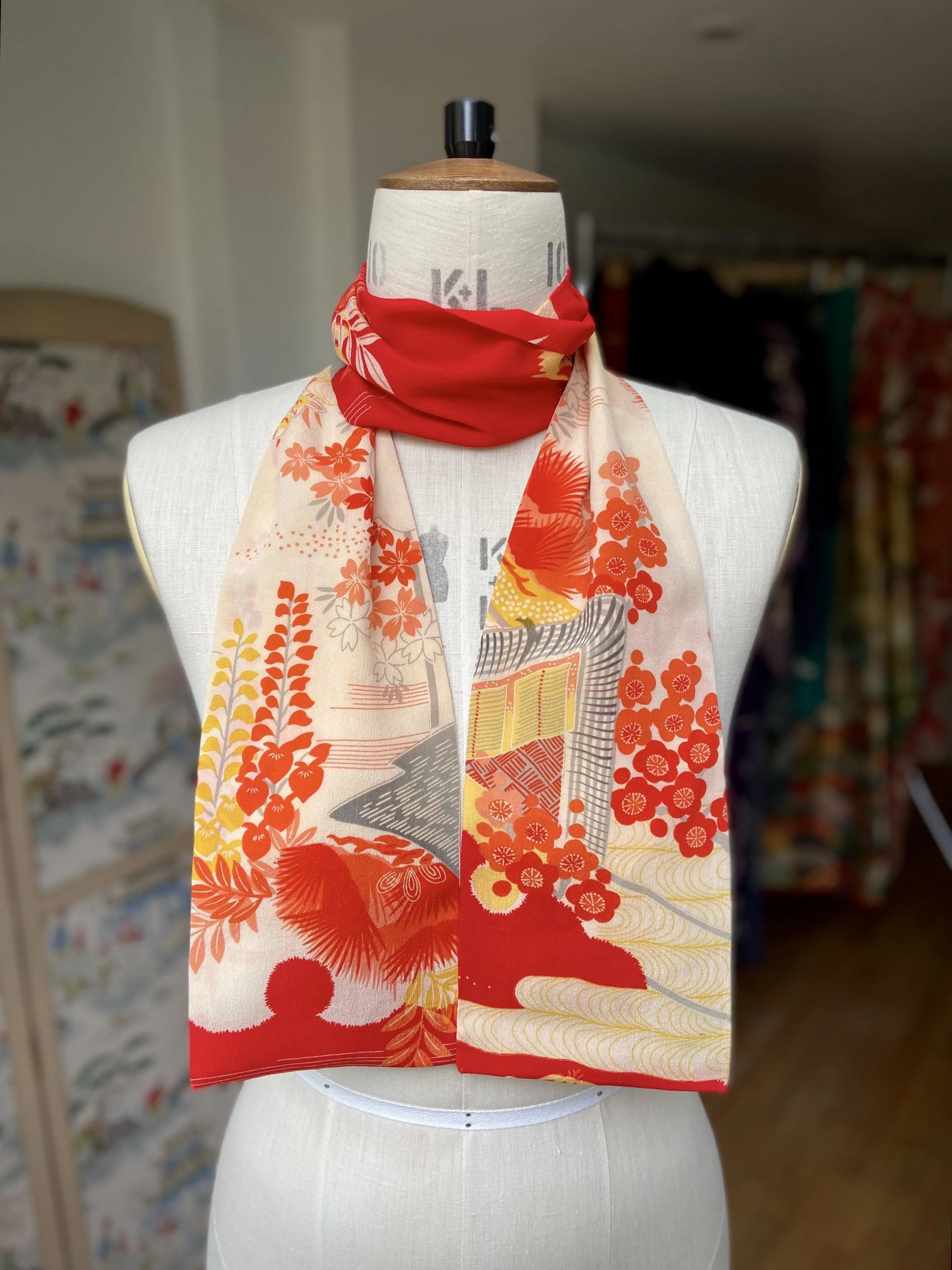 Bright vermillion red and yellow scarf presented on a dress stand, with printed blossom design, handmade from repurposed Japanese kimono crepe silk by Kirsty Chivers