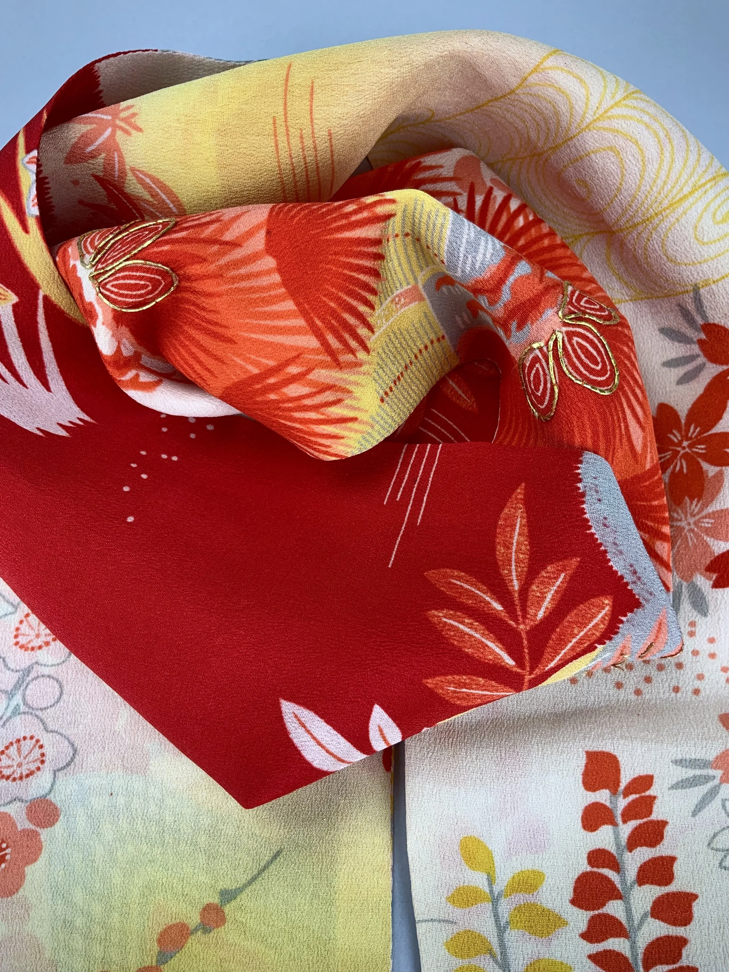 Closeup of vibrant red and yellow scarf with printed blossom design, handmade from repurposed Japanese kimono crepe silk by Kirsty Chivers