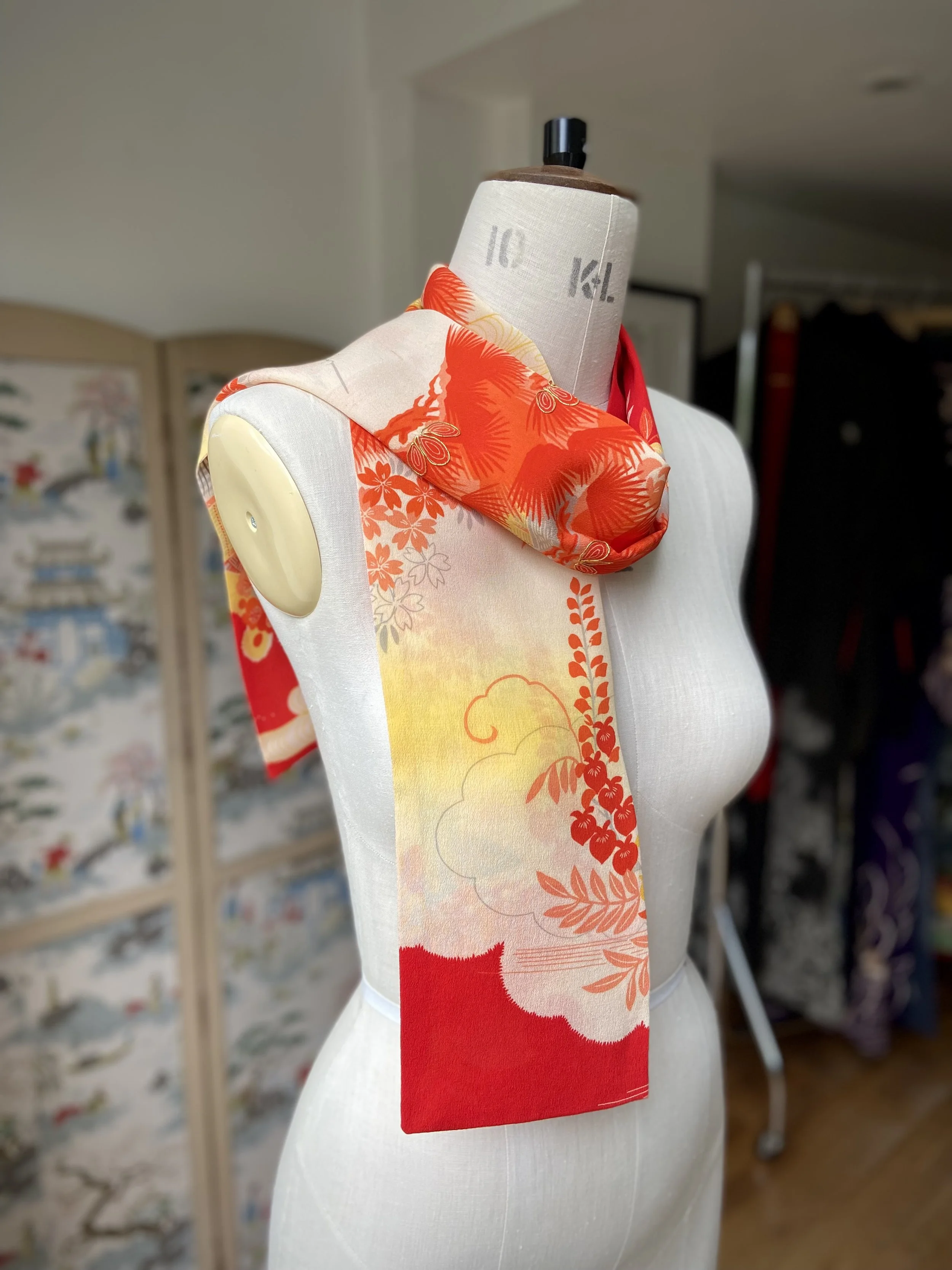 Bright vermillion red and yellow scarf presented on a dress stand, with printed blossom design, handmade from repurposed Japanese kimono crepe silk by Kirsty Chivers