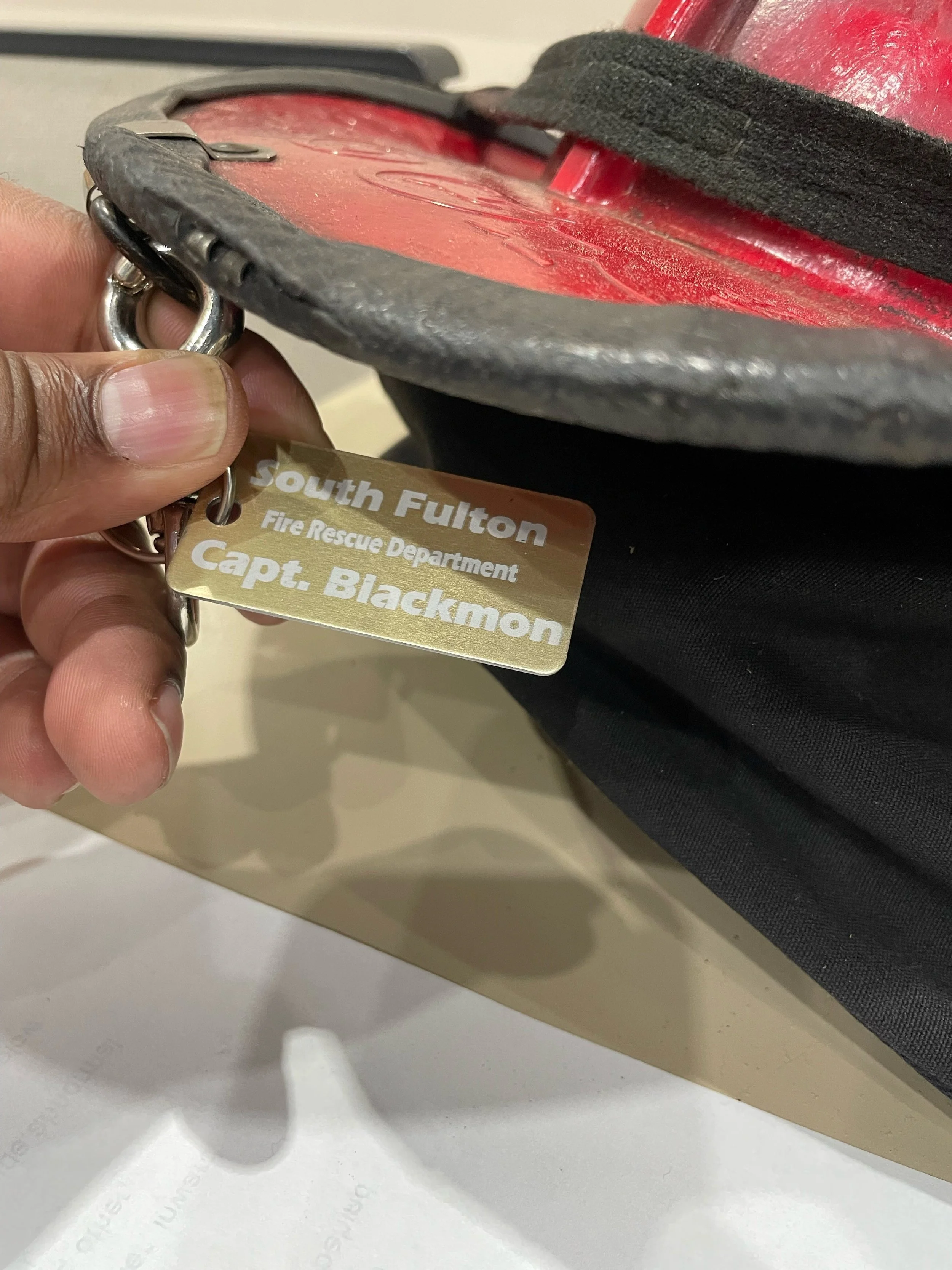 Firefighter accountability tag attached to helmet gear showing custom engraved name and department identification tag in use