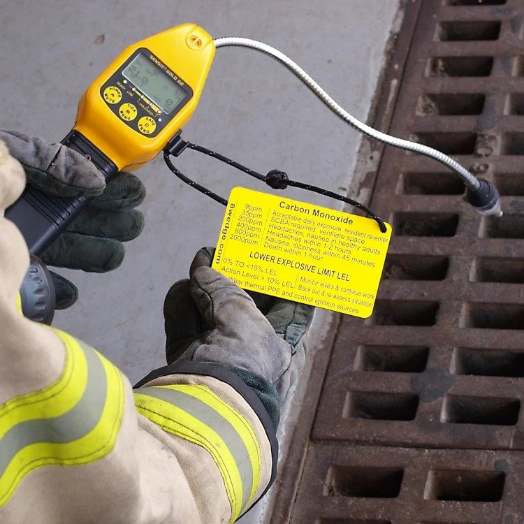 Firefighter using 4 gas monitor with reference tag for CO H2S O2 and LEL readings in confined space