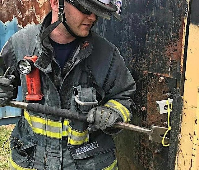 firefighter using wedge tool to force and maintain door gap during entry