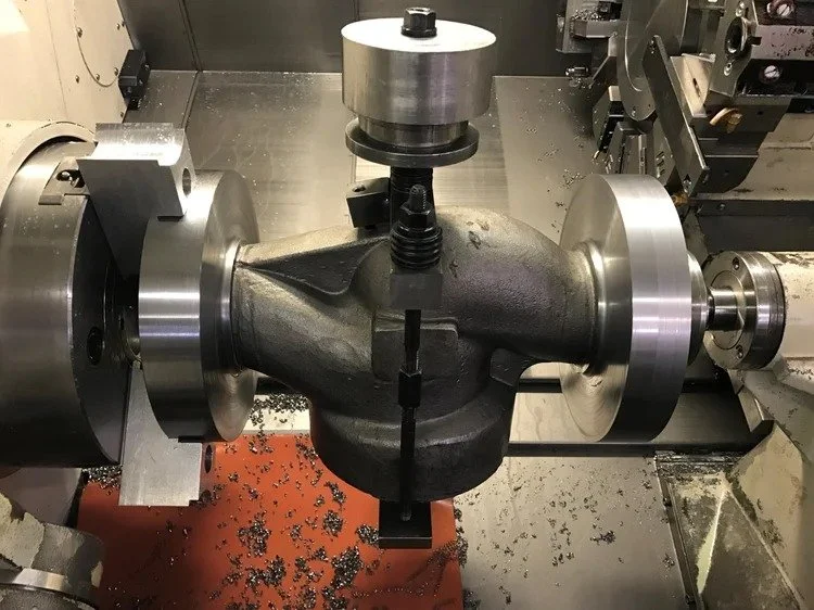 CNC machining valve body component secured in fixture during production