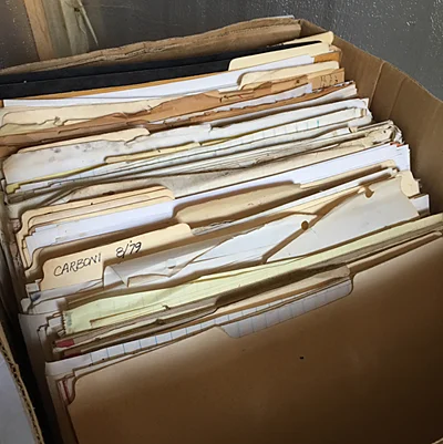 This is an example of typical box of archives; Manila folders and lined pads of paper, reprints of articles, newspaper clippings and random slips of paper, blank postcards and dry-cleaning receipts.