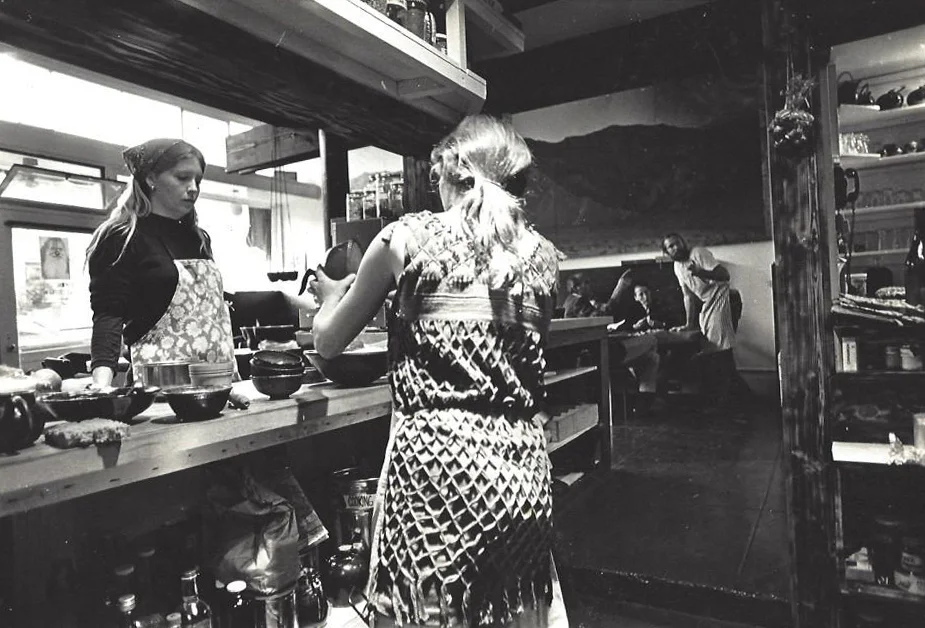 Co-owner/chef Jene LaRue explains the items on the chalkboard menu to a couple of patrons at The Diamond Sutra Restaurant. Behind Jene is the large painting by Noble Richardson; in the foreground is a view from the open kitchen, highly unusual at that time.
