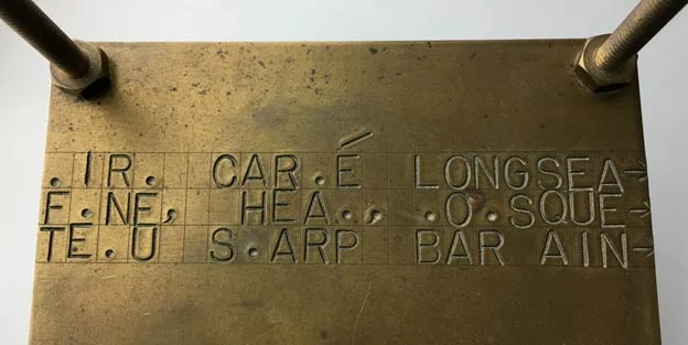Inscribed letters on one of the two brass plates of A Bruit Secret , between which sits a ball of twine enclosing an object placed within by his friend Walter Arensberg, the nature of which Duchamp was not told nor about which did he inquire.