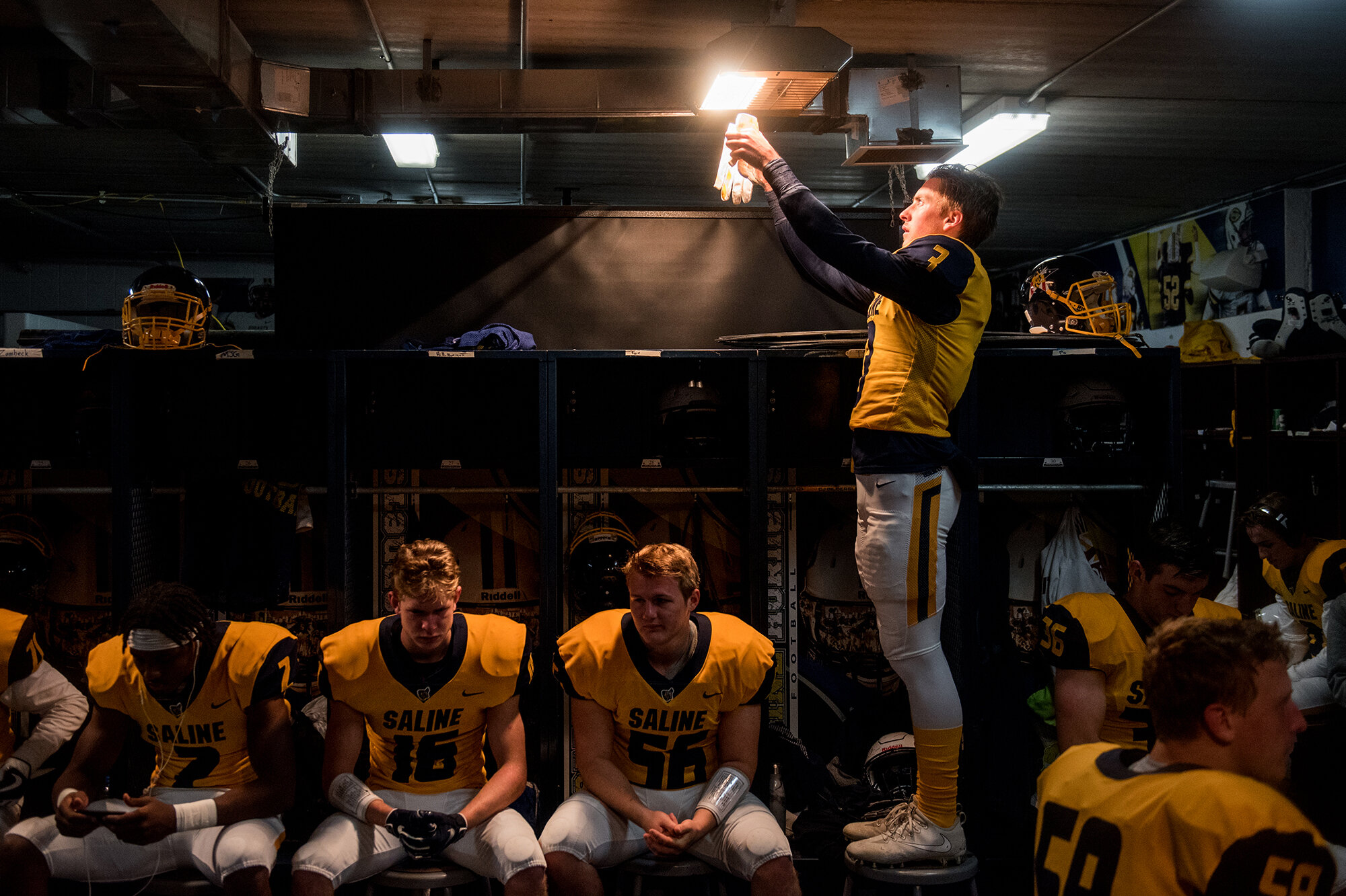  Saline’s Lucas Ebert, right, warms his gloves in the locker room before the high school football game between Saline and Monroe, Friday, Oct. 12, 2018 in Saline, Michigan. 