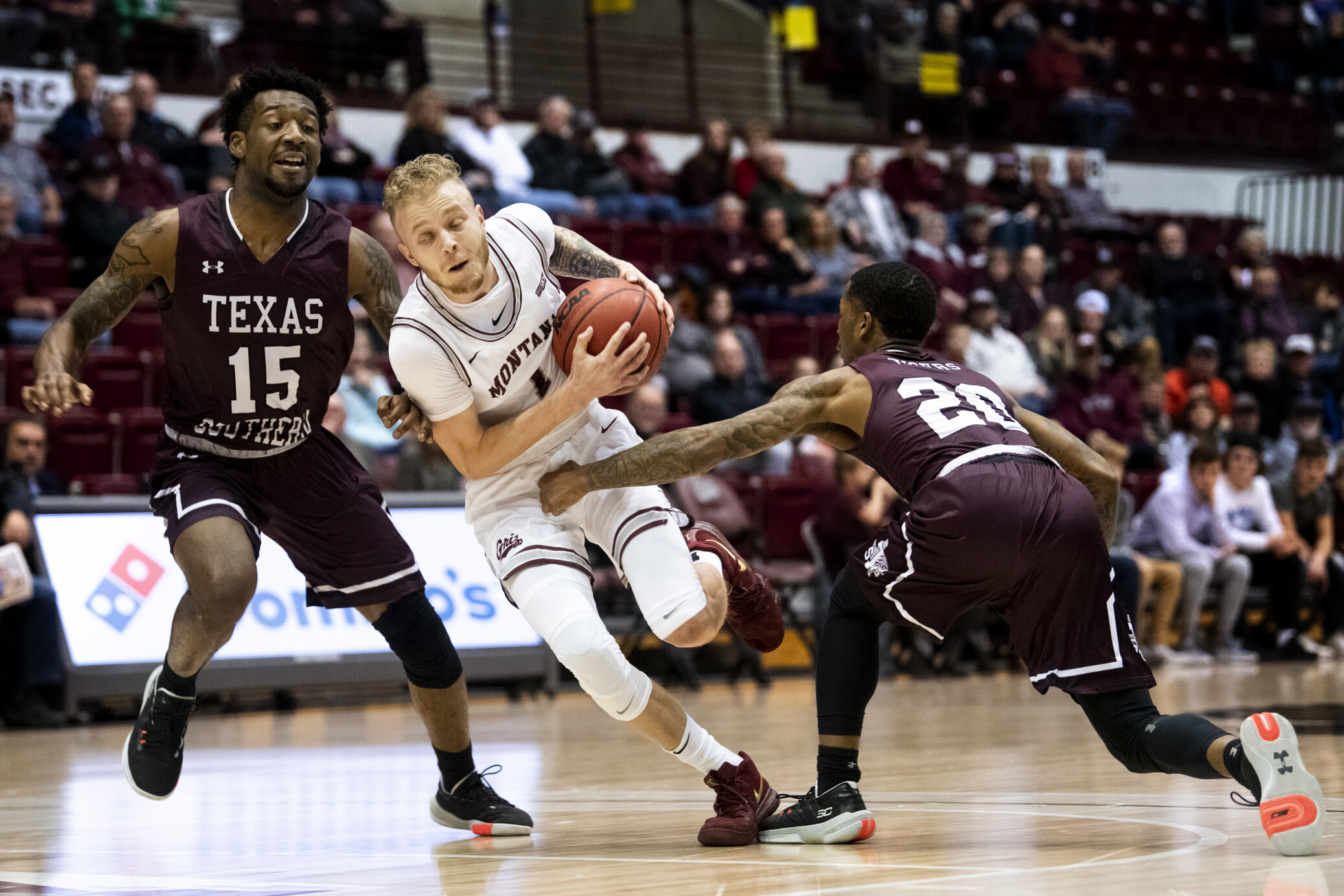  Montana's Timmy Falls, middle, drives the ball between Texas Southern's Justin Hopkins, left, and Tyrik Armstrong, right during their game at Dahlberg Arena, Nov. 25, 2019 in Missoula, Mont. 
