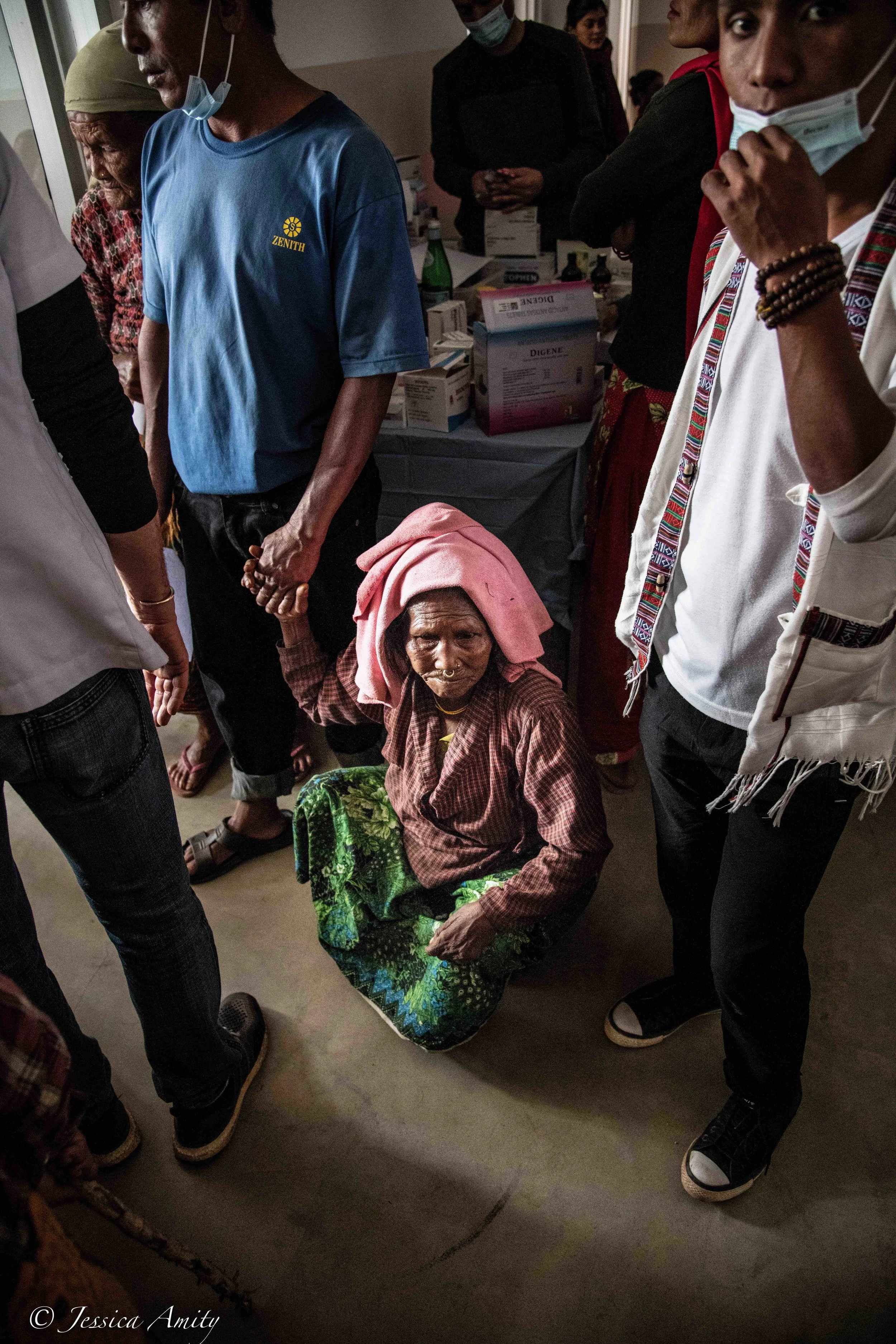 Although you are unable to see from this photo, the woman pictured is unable to walk. Her feet and toes are all misaligned. I was told later that this might have been a result of a broken bone that was not treated and thus had not healed correctly. She holds her sons hand for support before seeing the doctor.