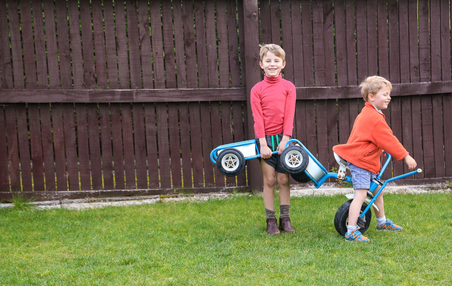 brothers-playing-together-with-trike-in-garden.jpg
