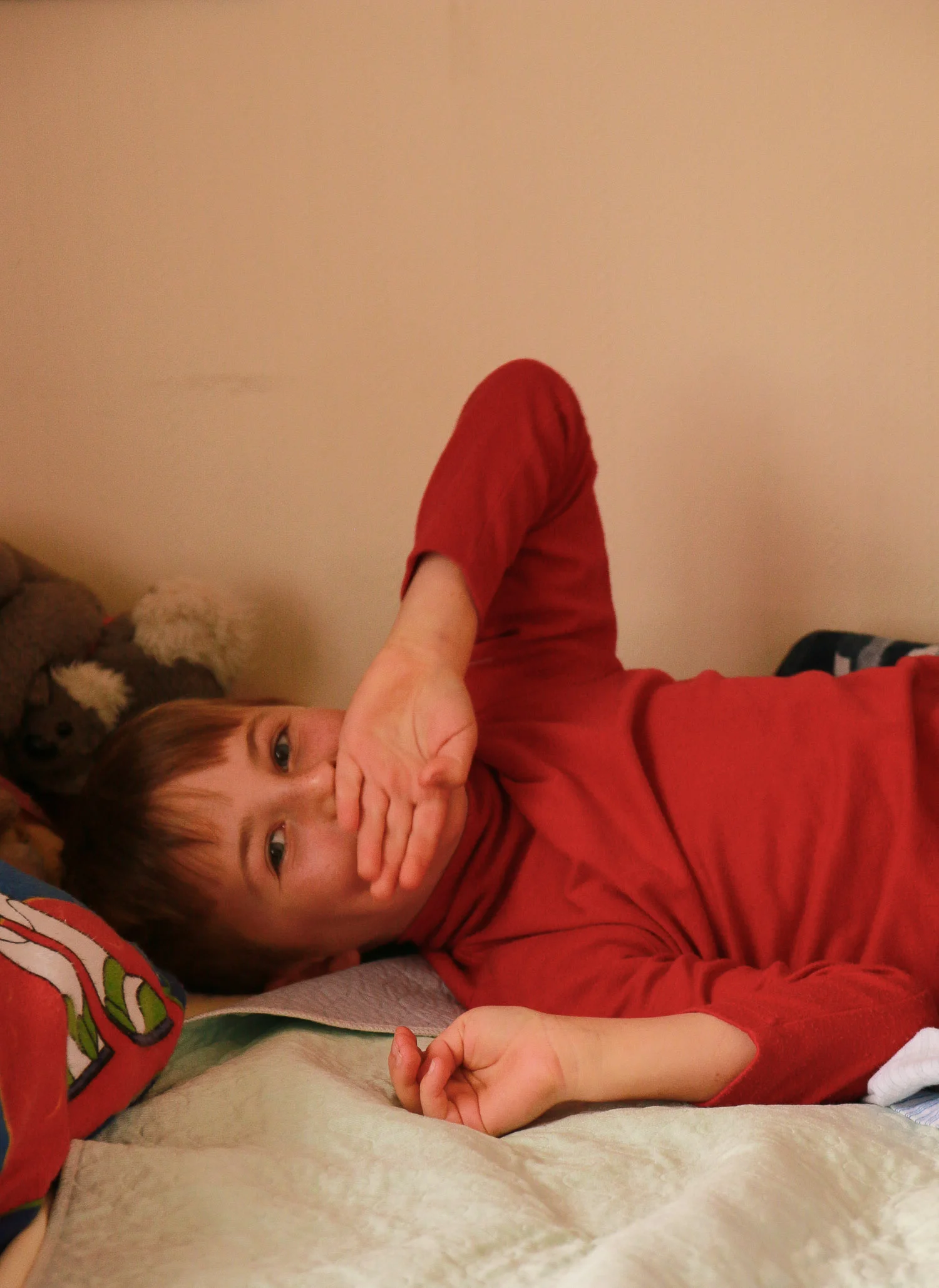 young-boy-wearing-red-lying-on-bed-looking-at-camera.jpg