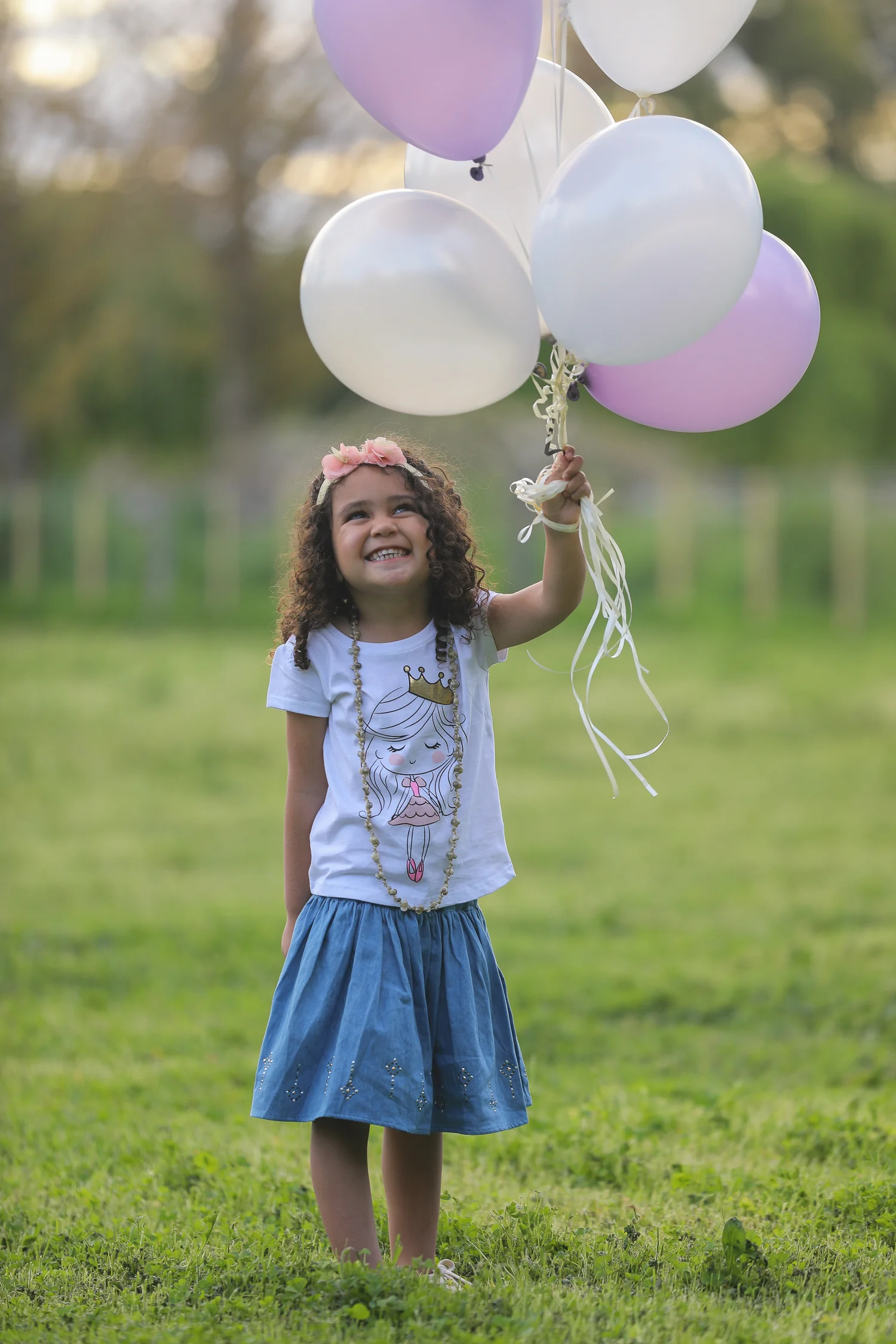 little girl holding balloons above her head