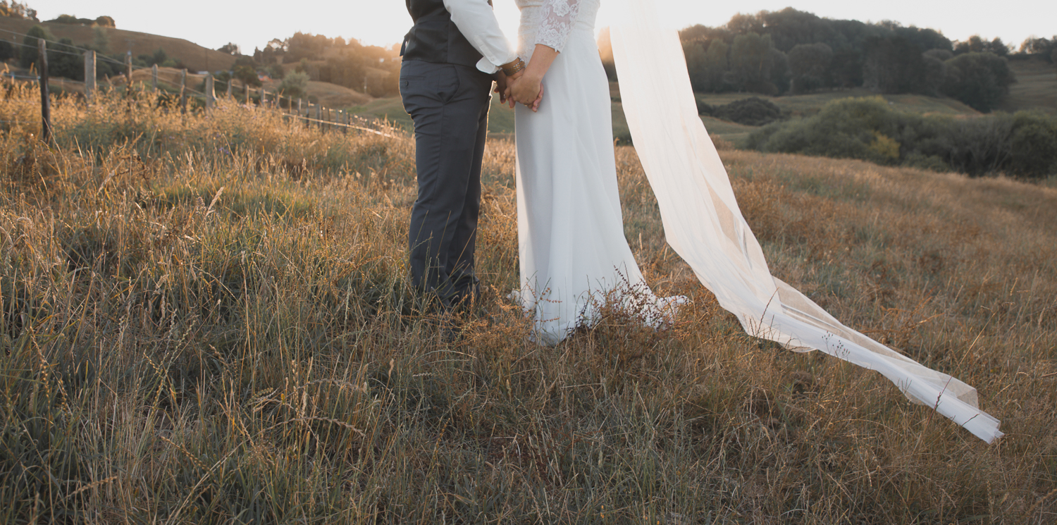 bride and groom walking on wedding day in long grass