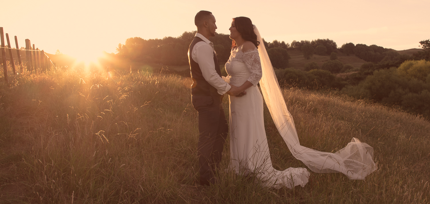 bride and groom standing together at sunset