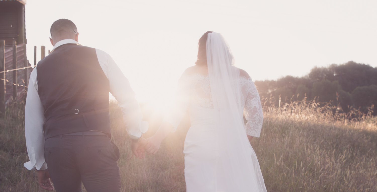 bride and groom walking into sunset on wedding day
