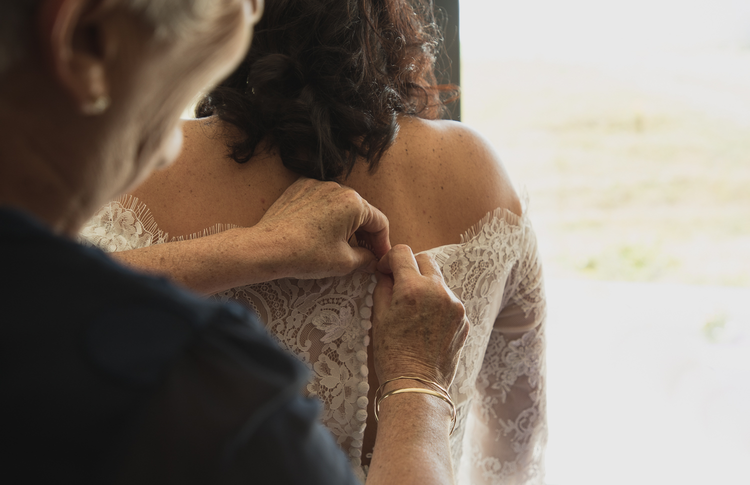 mother of the bride buttoning up wedding dress