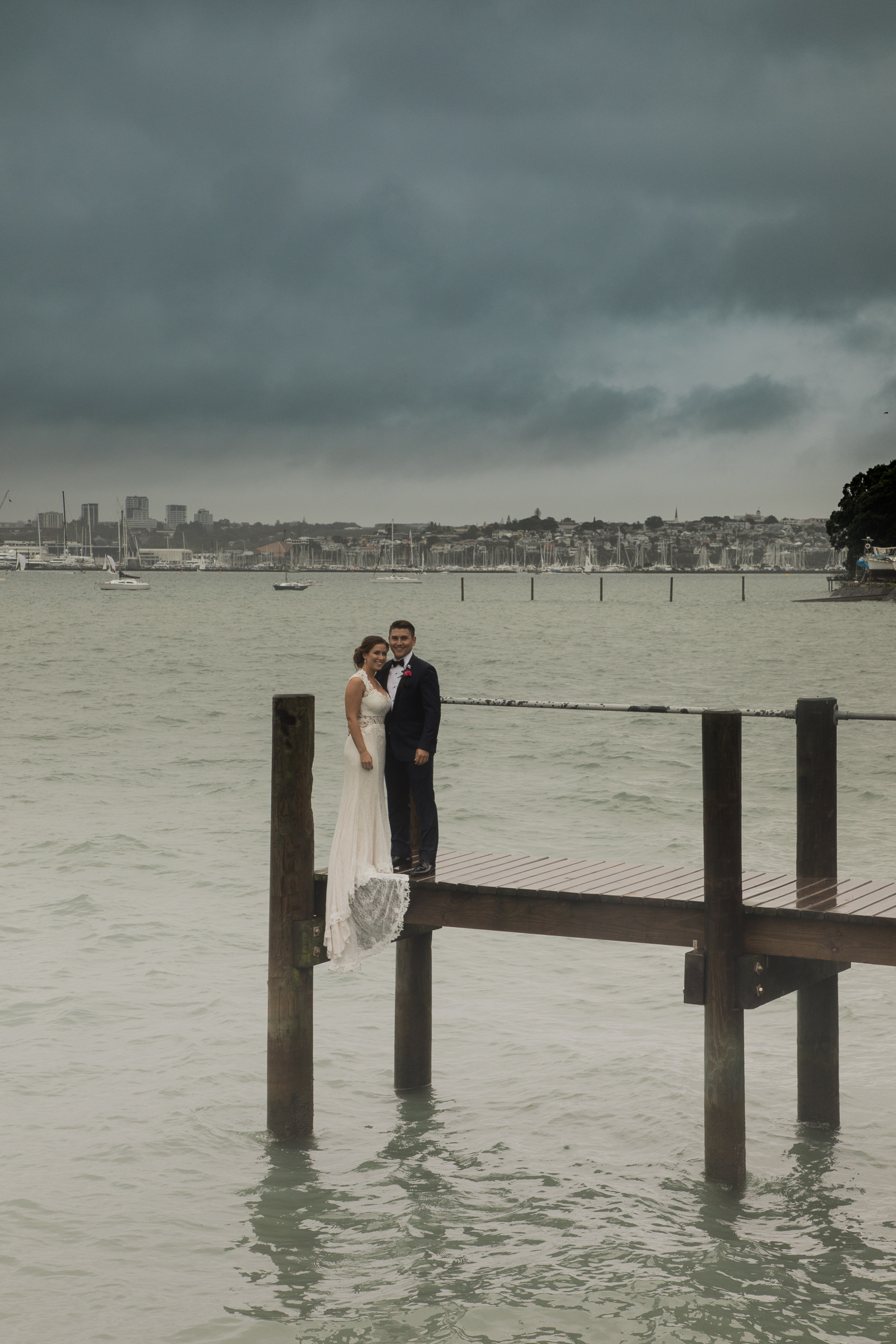 bride and groom on wharf overlooking Auckland city