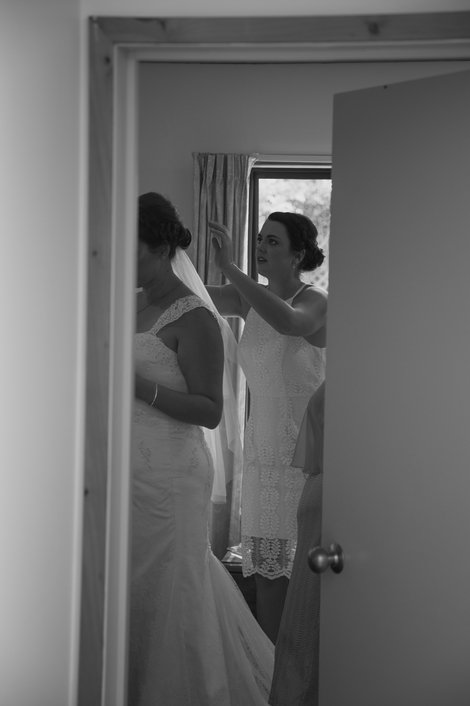 maid of honour helping bride with veil on wedding day