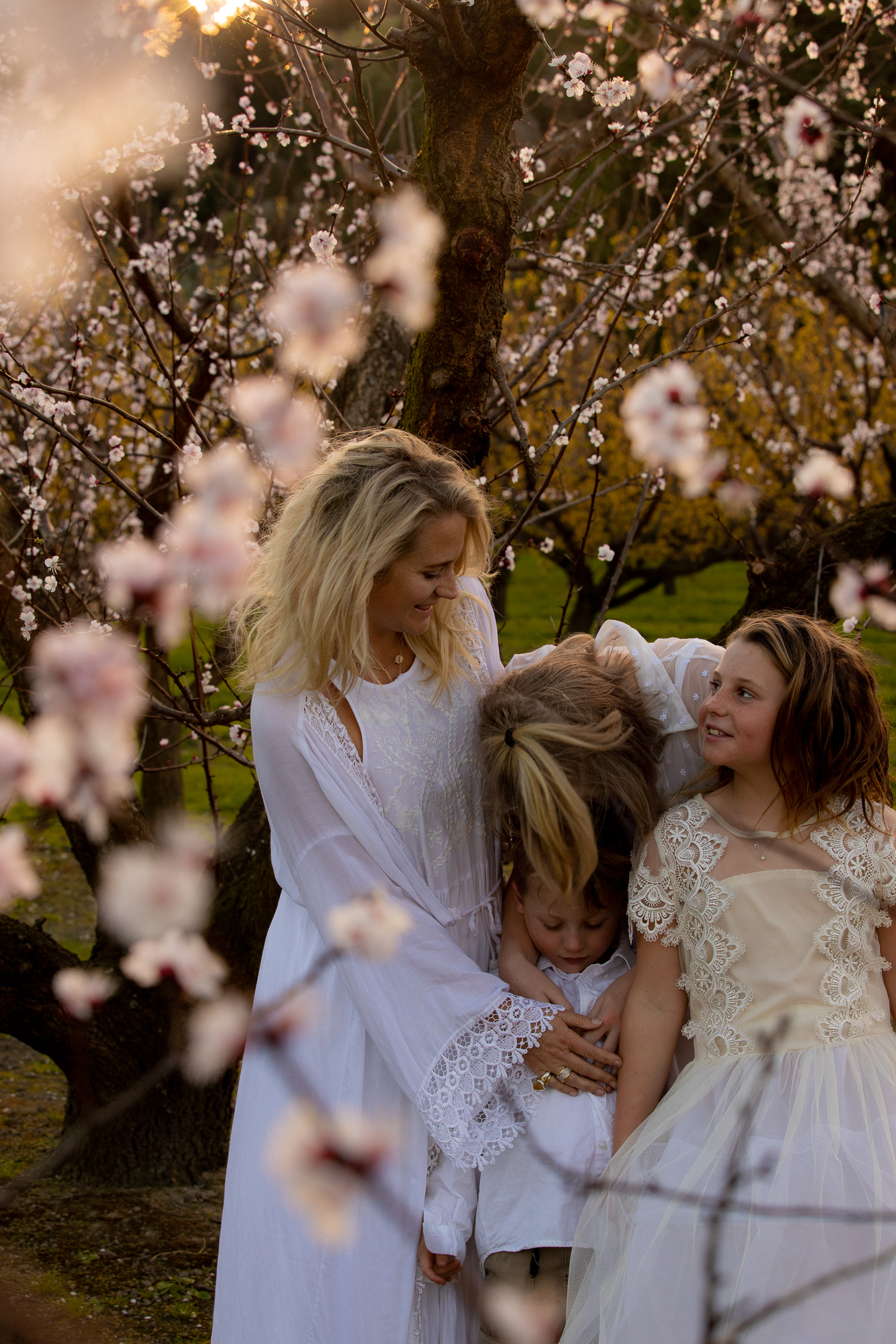 Hawkes-bay-photographer-at-sunset-in-orchard-in-the-blossoms-laughing-together-mother-with-her-children.jpg