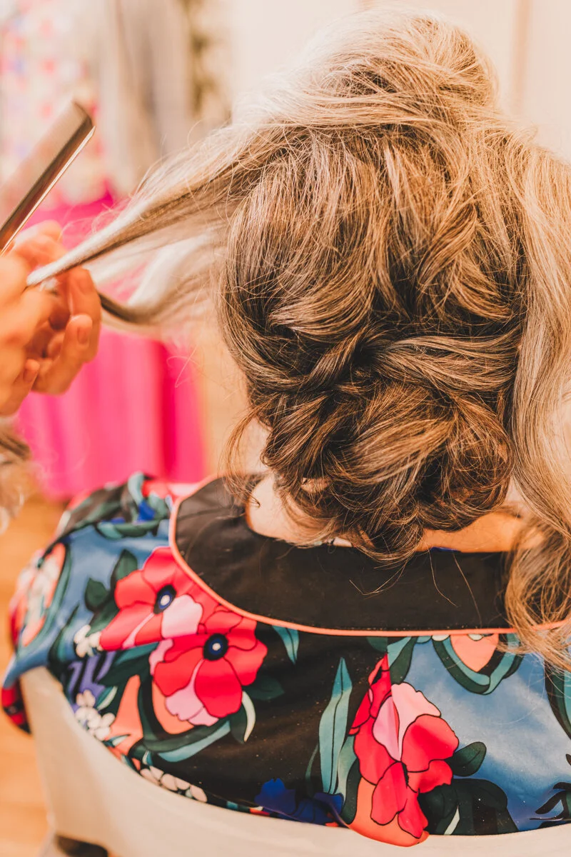bride getting hair done on morning of wedding
