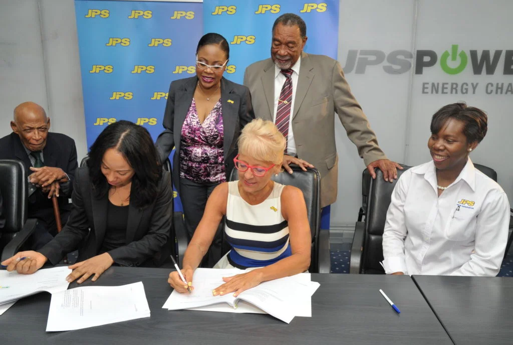 Mayor of Savanna-la-Mar, Councillor Bertel Moore and JPS Legal Counsel Teri-Ann Gibbs (standing), closely observe as JPS President & CEO, Kelly Tomblin (2nd right) signs a Power Purchase Agreement with Angella Rainford of Eight Rivers Energy. Under the agreement, JPS will purchase power from the solar provider, for 20 years, up to the year 2038. The solar plant, which will be constructed in Paradise, Westmoreland will generate 37MW of electricity. Looking on are Attorney at Law, Frank Phipps (far left) and JPS Manager for Special Projects, Dionne Nugent.