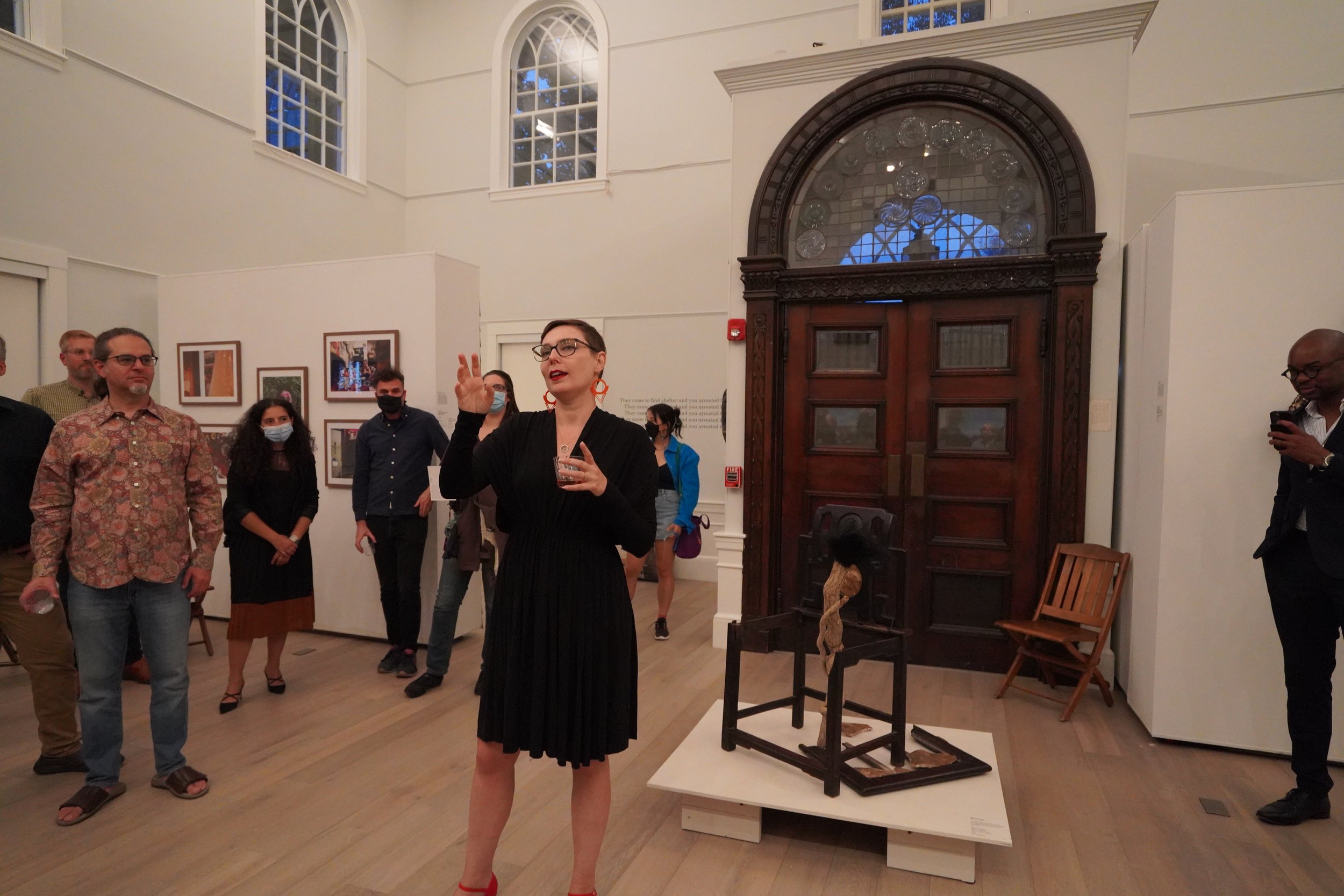 Julia Csekö, curator of "Sanctuary City" at Somerville Museum giving a gallery talk in front of "Have a Seat", an installation by Wen-hao Tien, September 2022.