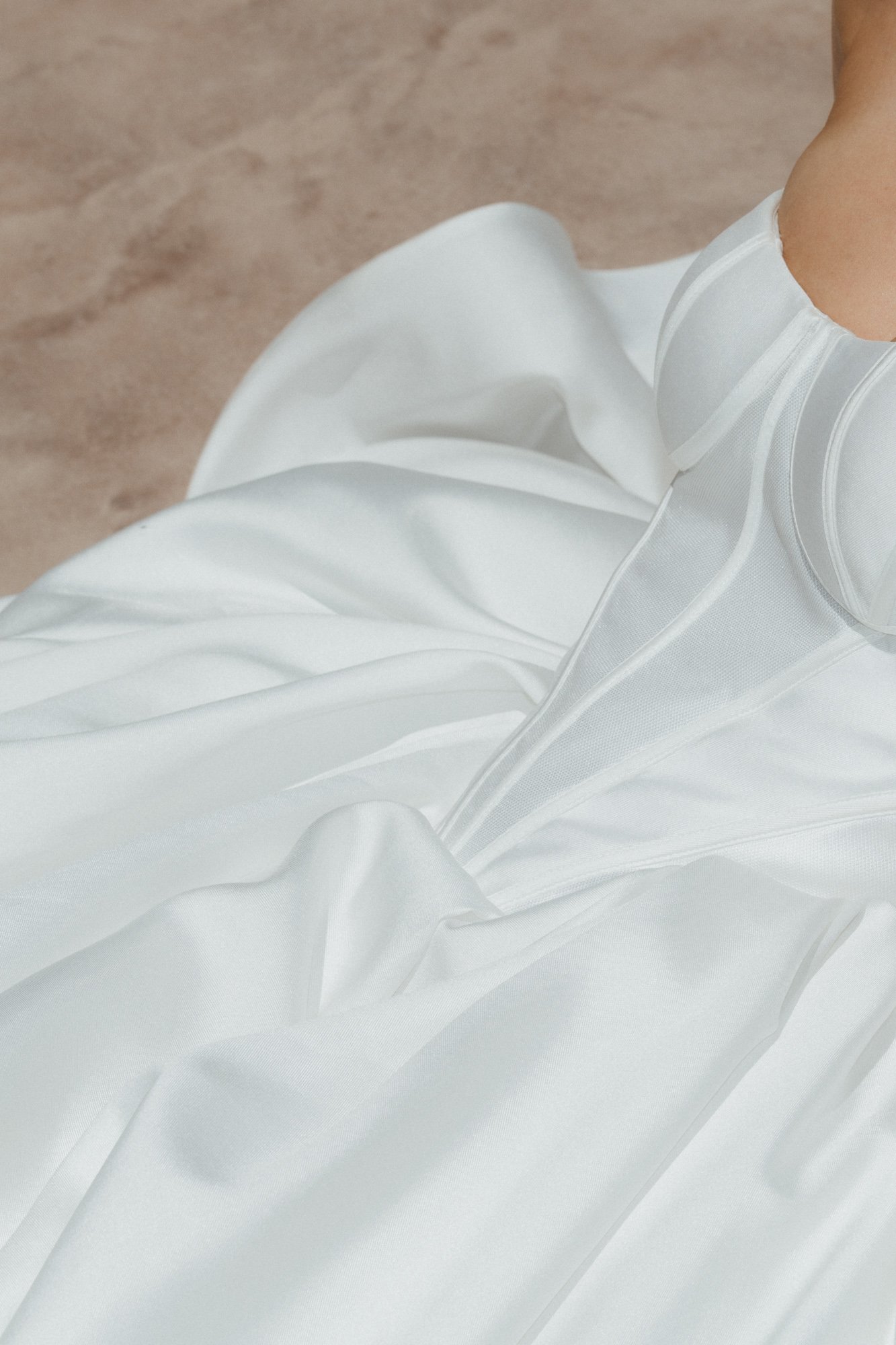 Close-up detail of white wedding dress bodice and seaming against warm neutral background