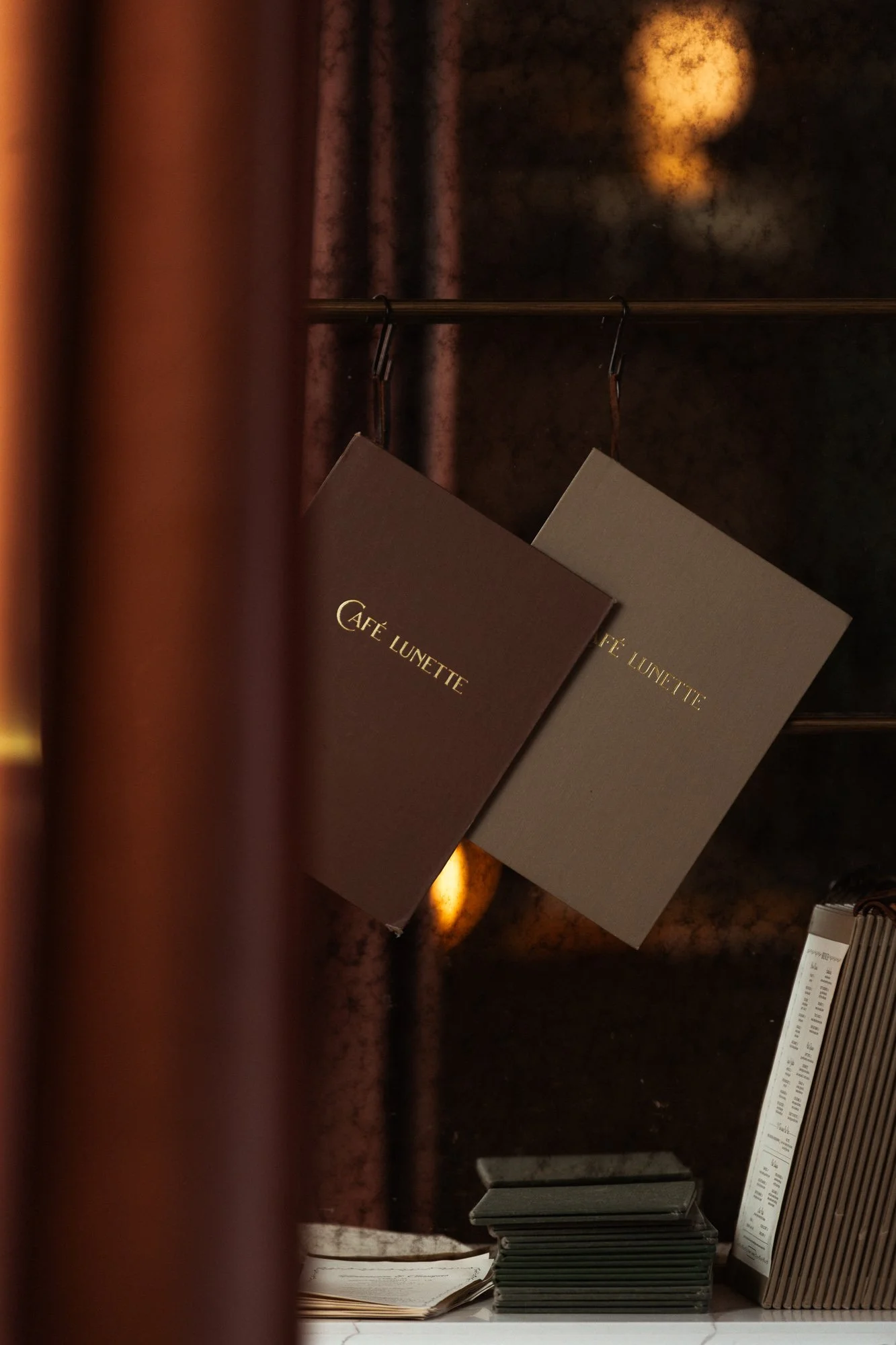 Two menus from Cafe Lunette hanging inside a dark, cozy cafe or restaurant.