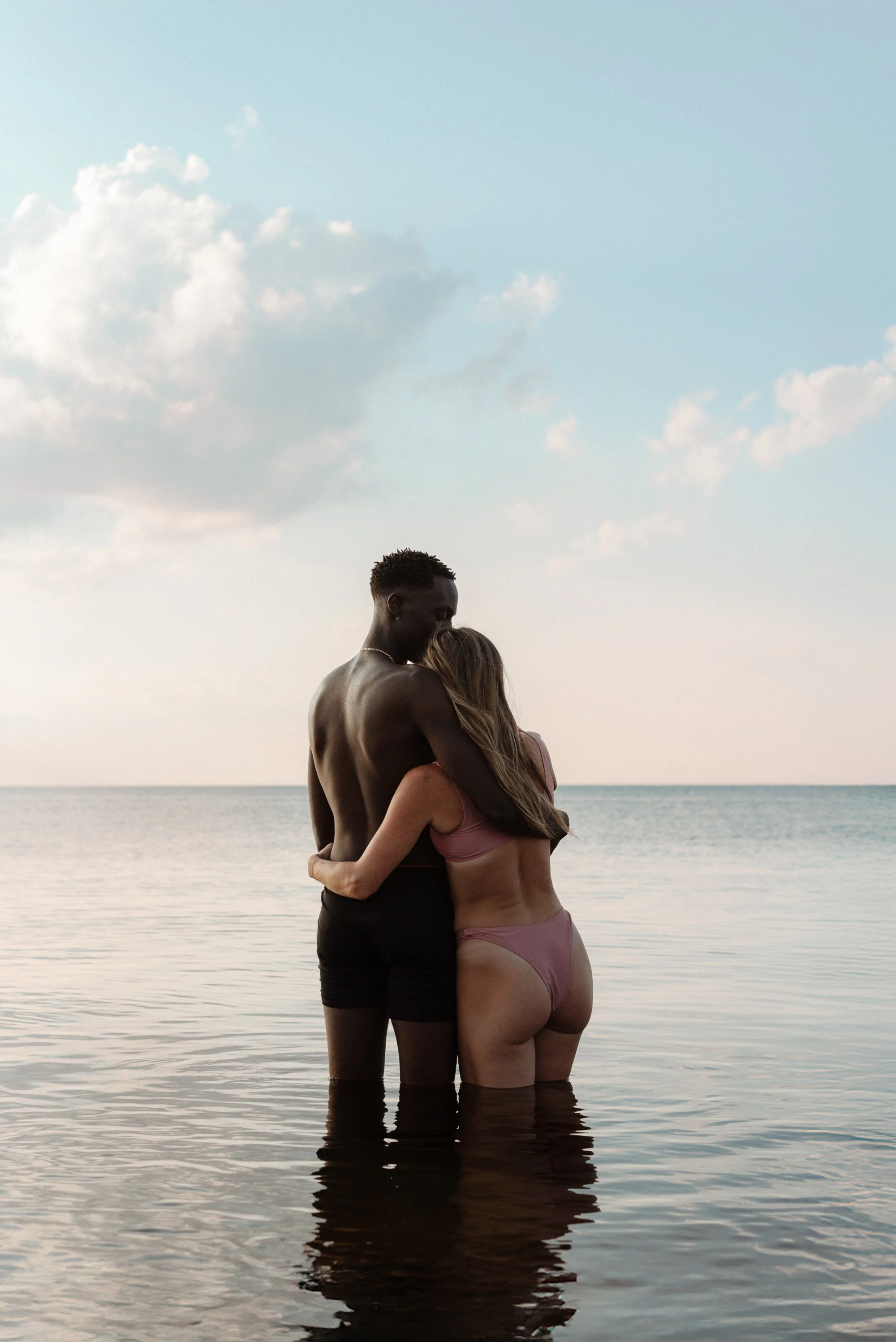 Couple embracing in the ocean at sunset during a beach portrait session in Cape Breton