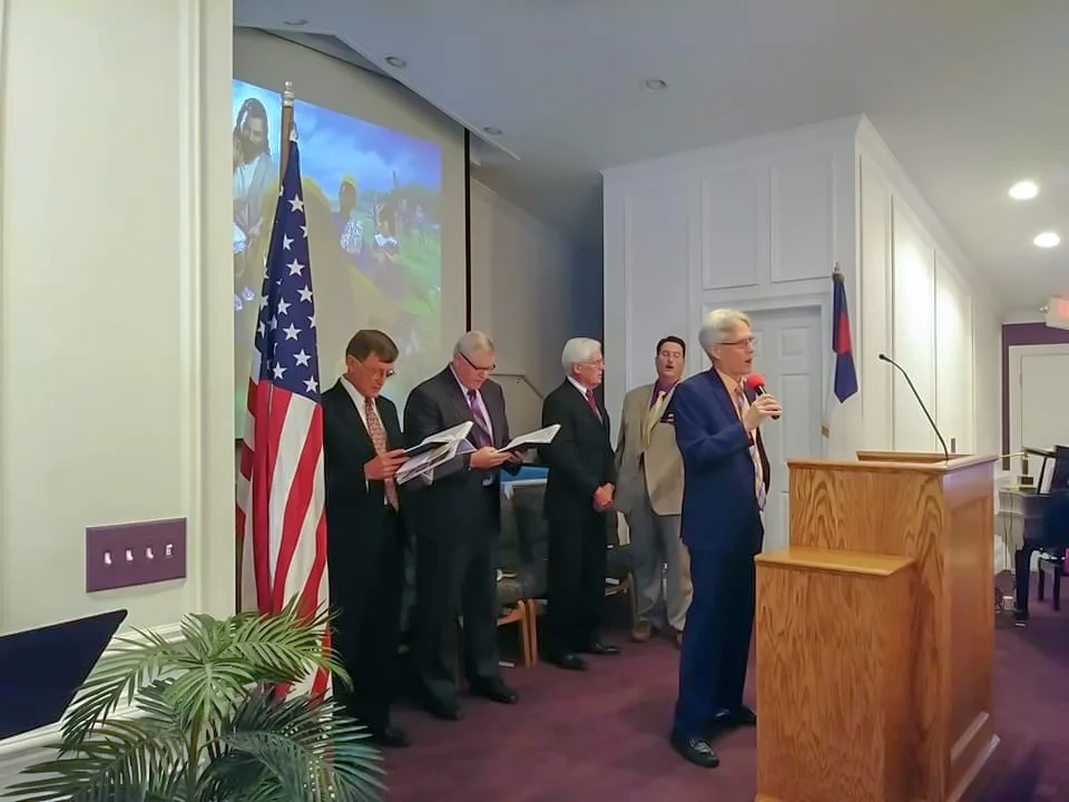 Mike Duman, pastor, leads a congregational song while Dennis Milburn (left), former treasurer of Gulf States, Dave Livermore, president of the Gulf States conference, Mel Eisele, former president of Gulf States, and Michael Abraham, local elder, sing along for the ceremony.”