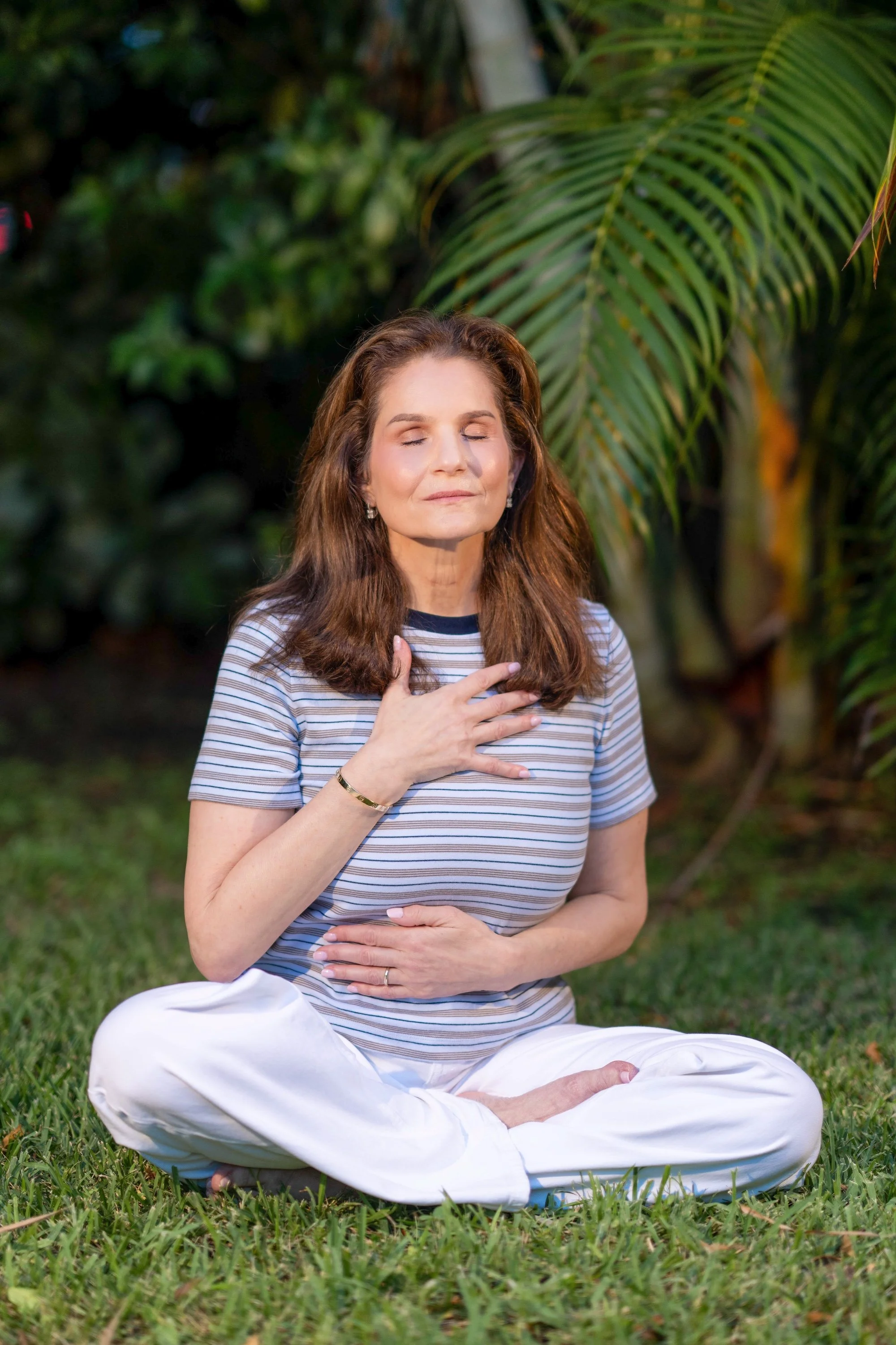 Women with brown hair taking a deep breath which sitting in green grass | What is Somatic Coaching?