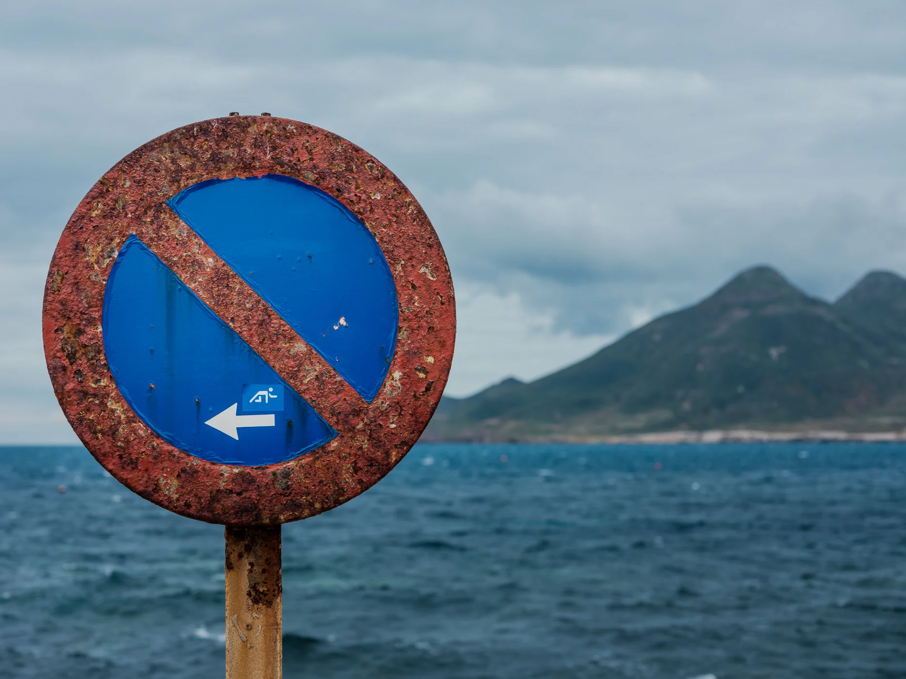 Fujifilm GFX50S with the GF63mm f/2.8 - iso 100 - 1/200 - f/5.6 Details sometimes tell the story better than the big picture. This weathered no parking sign is proof that the gentle Mediterannean coast can be pretty rough too. The little sticker on the sign is a bonus. 