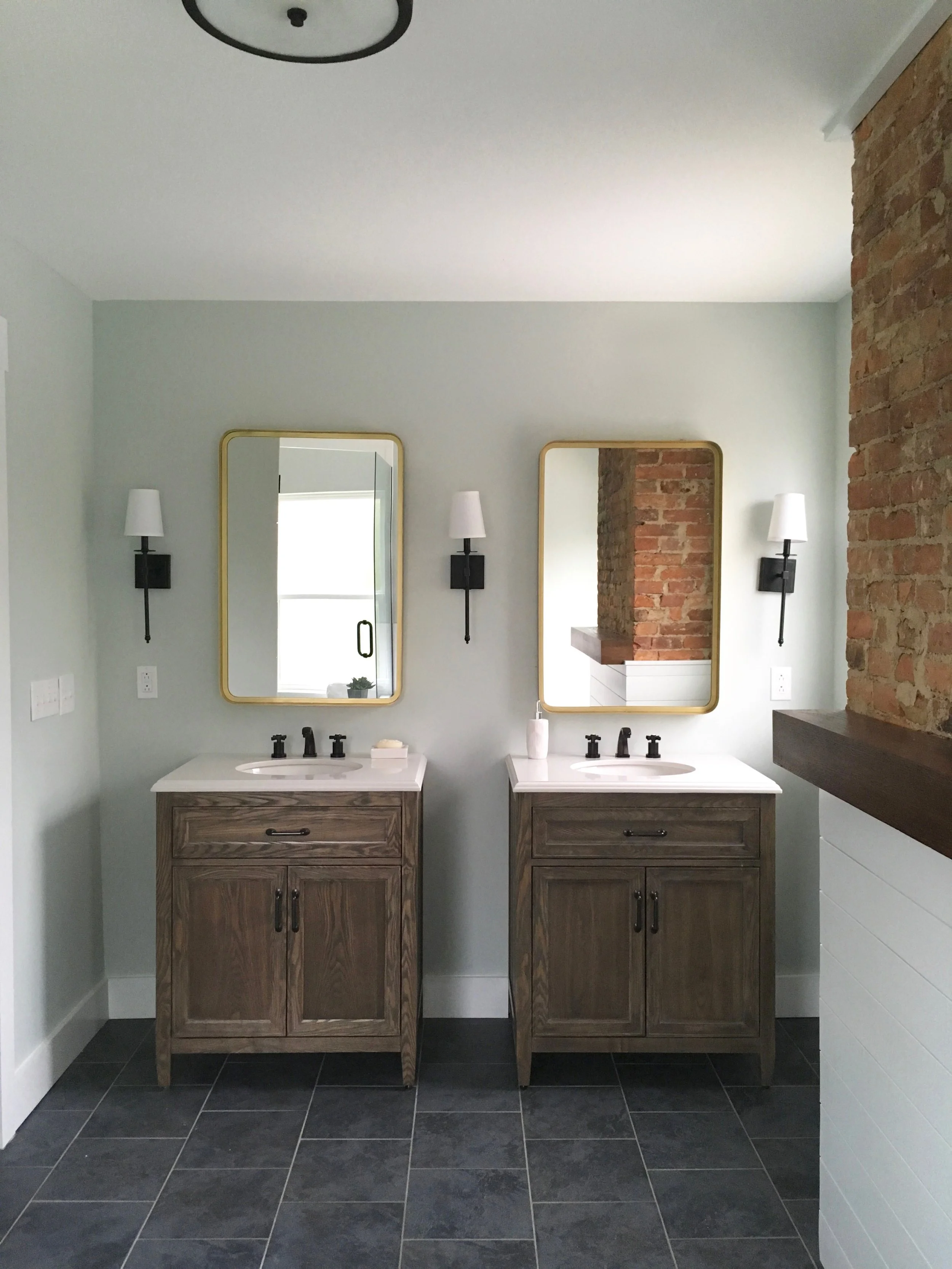 After: dual vanities create balance and symmetry. The glass door to the walk-in shower is visible in the left mirror.