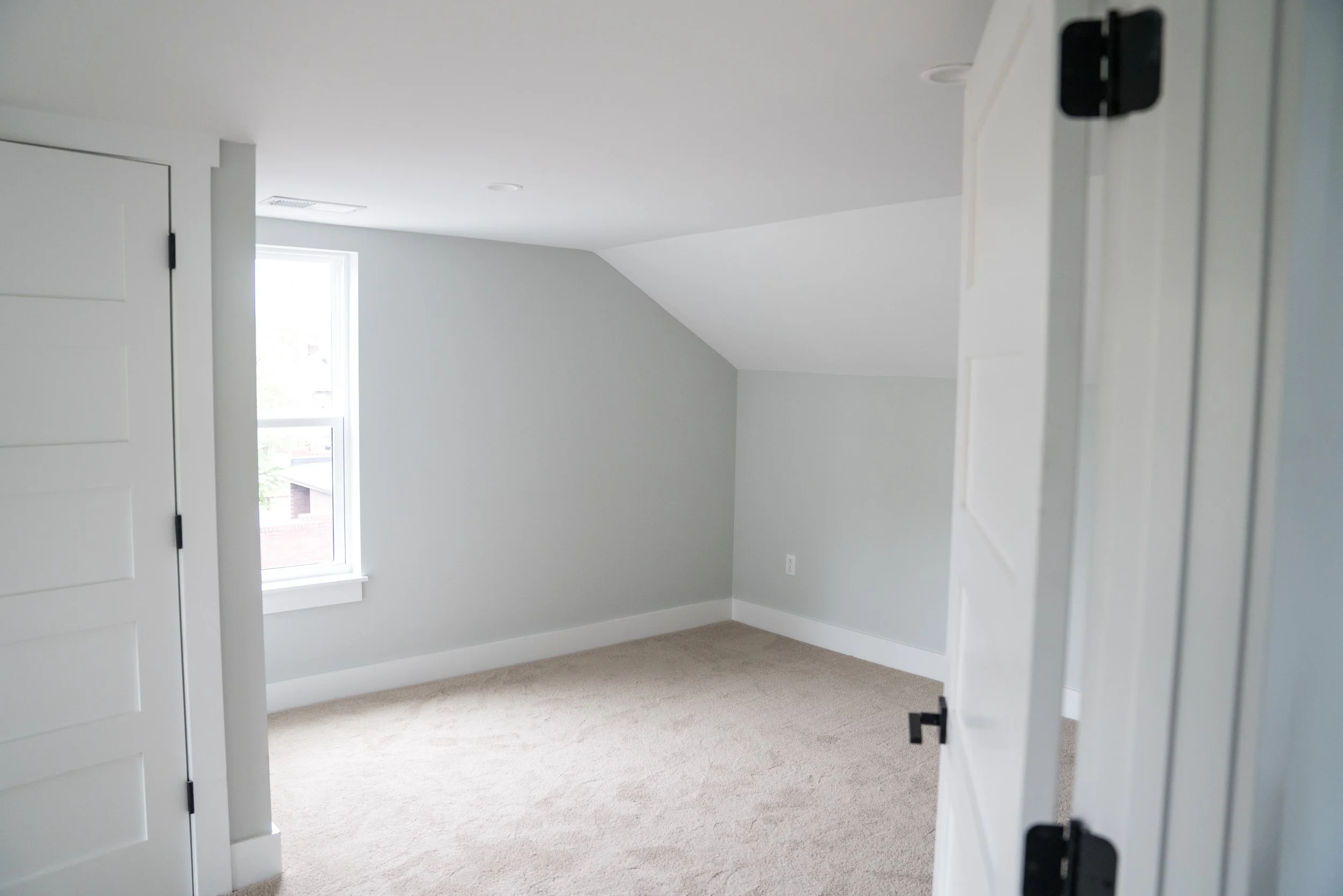 After: two cramped bedrooms were combined into a single larger bedroom by removing the dividing wall and brick fireplace stack. A walk-in closet was tucked under the sloped ceiling line on the left.