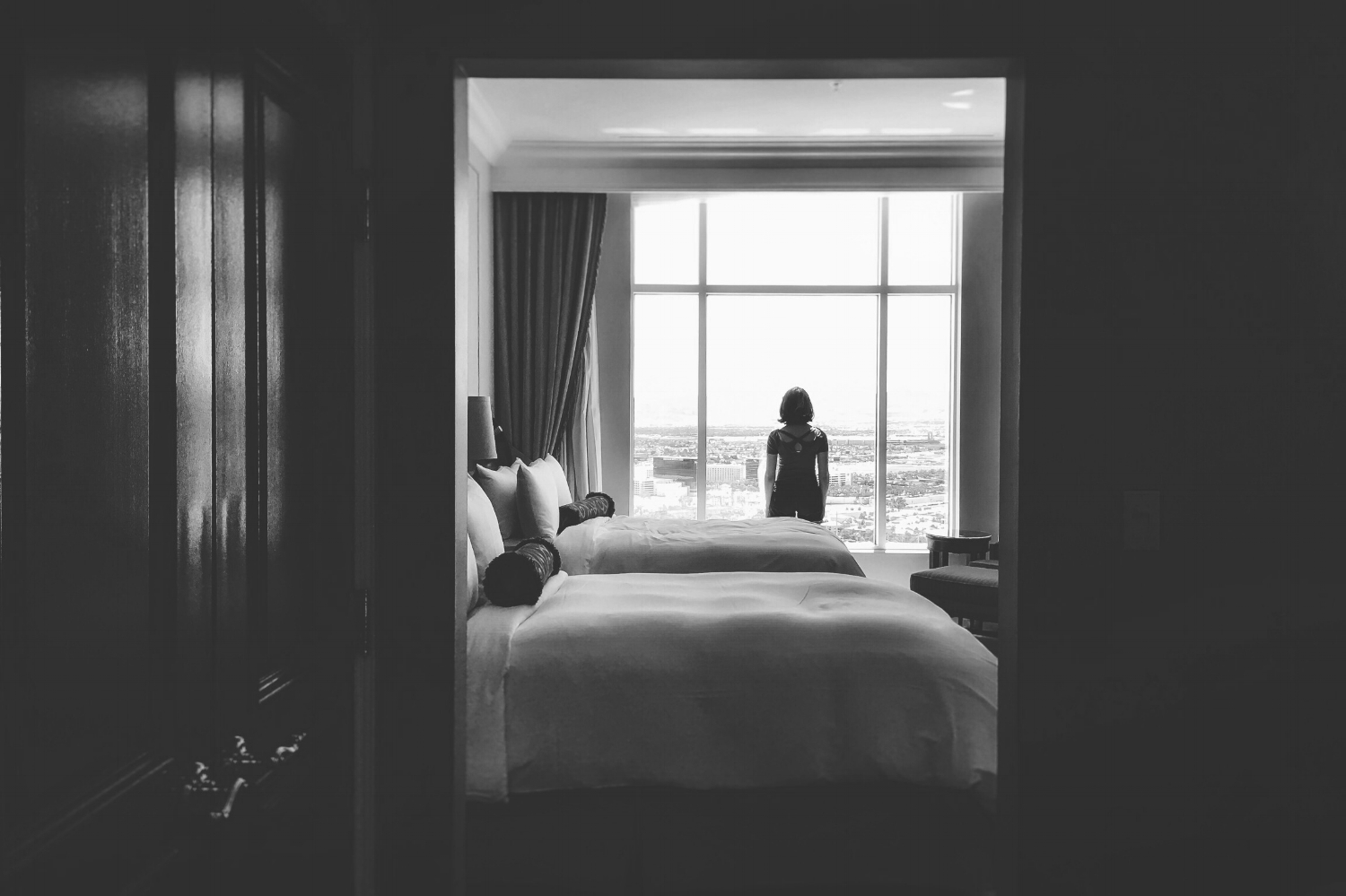 Woman gazing out window of clean hotel room