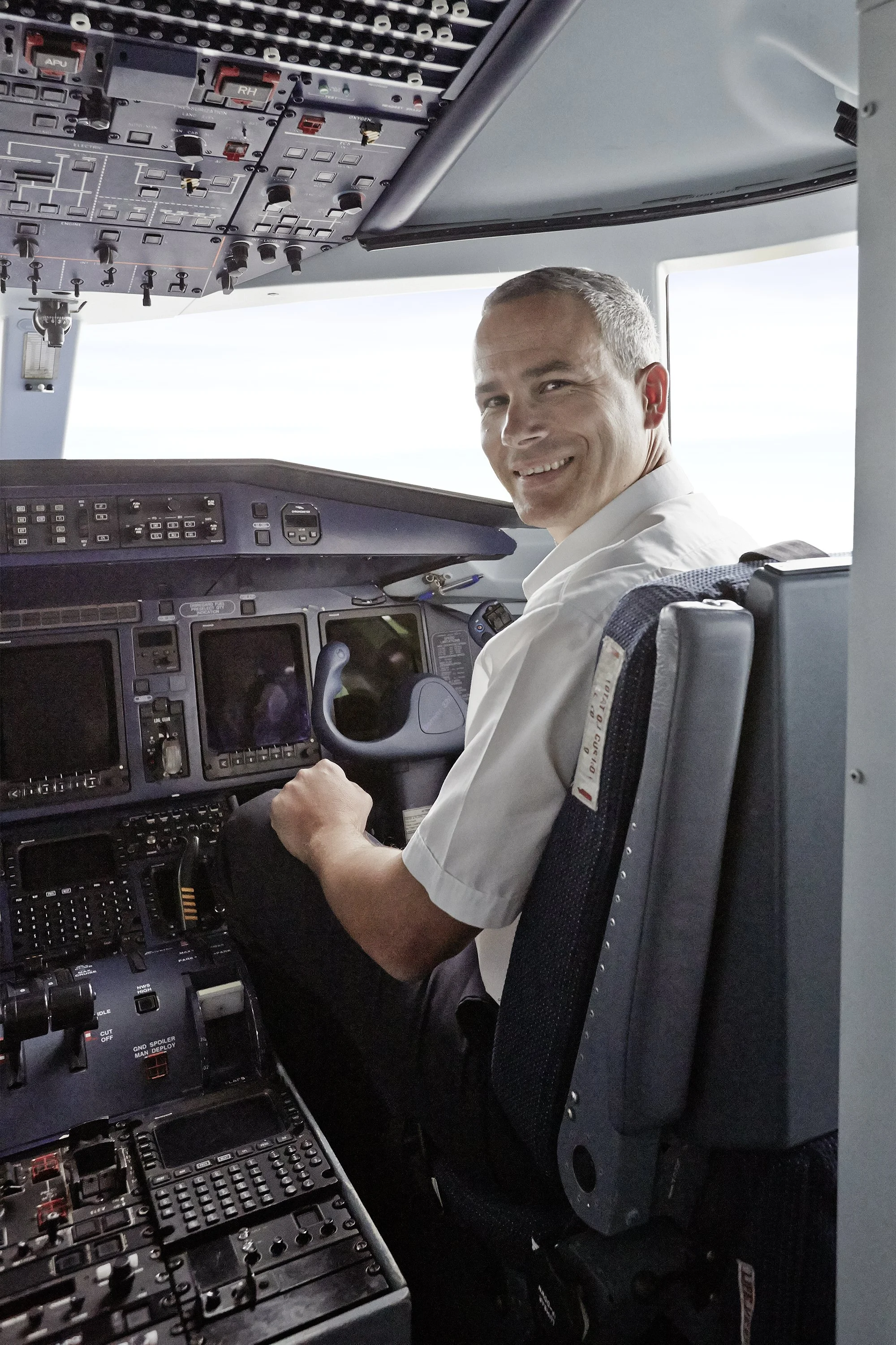 Pilot im Cockpit eines Flugzeugs, der nach hinten schaut und lächelt.