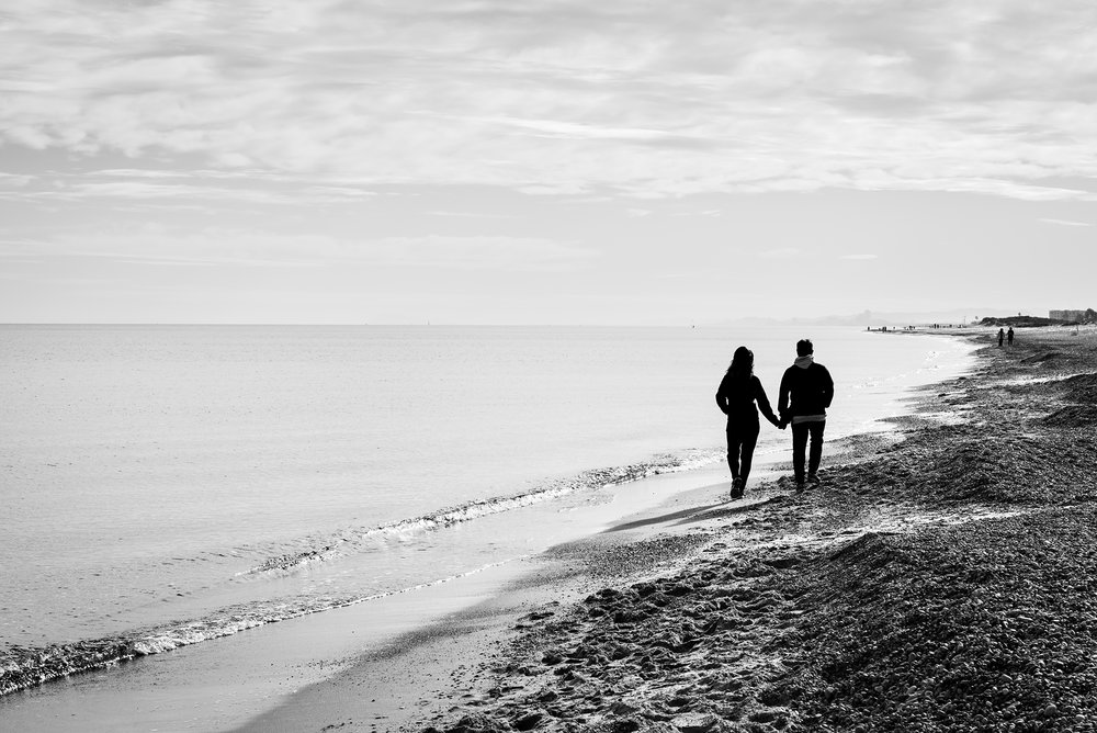 Silhouette of a couple holding hands while walking along the shore of the Mediterranean sea