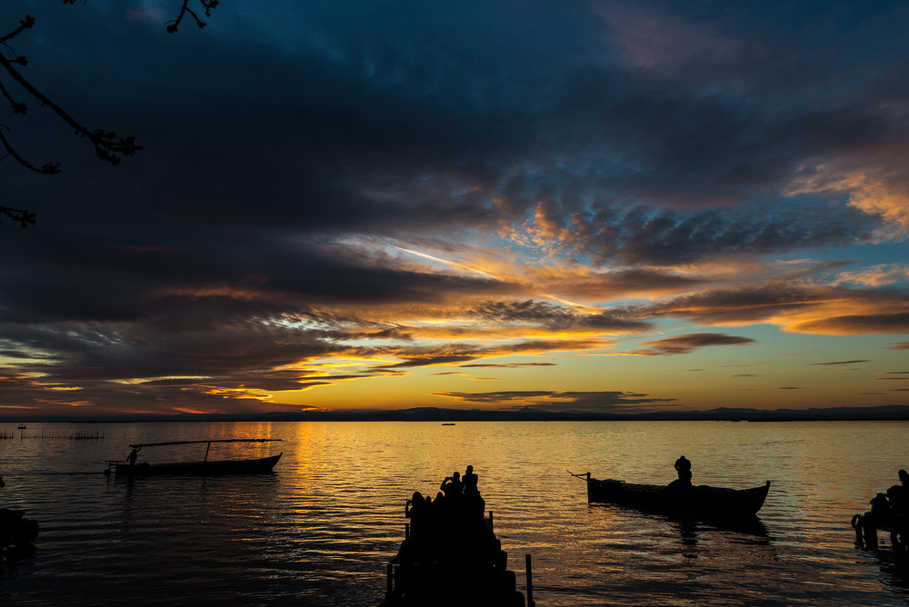 Silhouette of small traditional boats and tourists at dusk in the Albufera