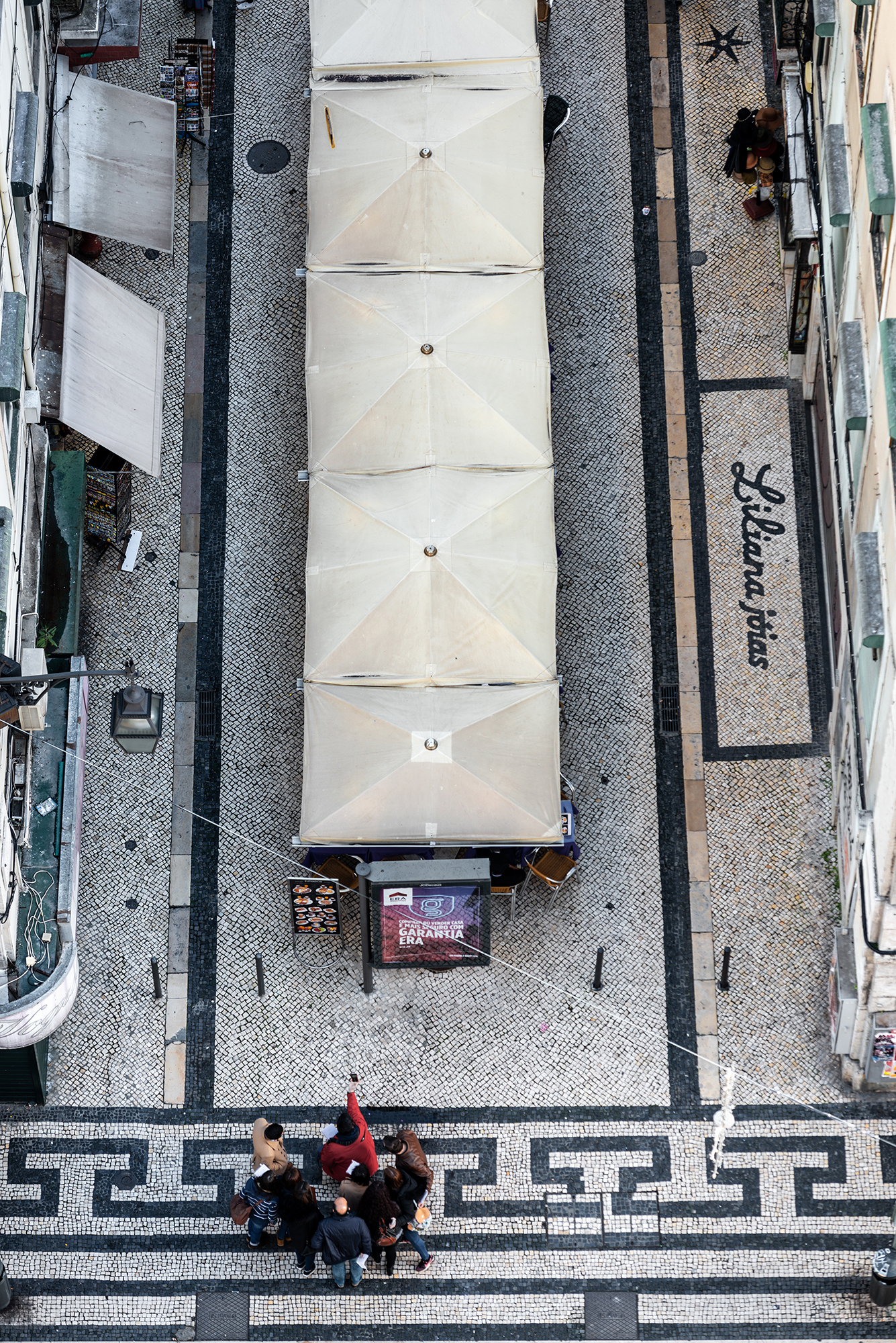 Aerial view of a group of tourists entering a traditional narrow cobblestone street in Baixa