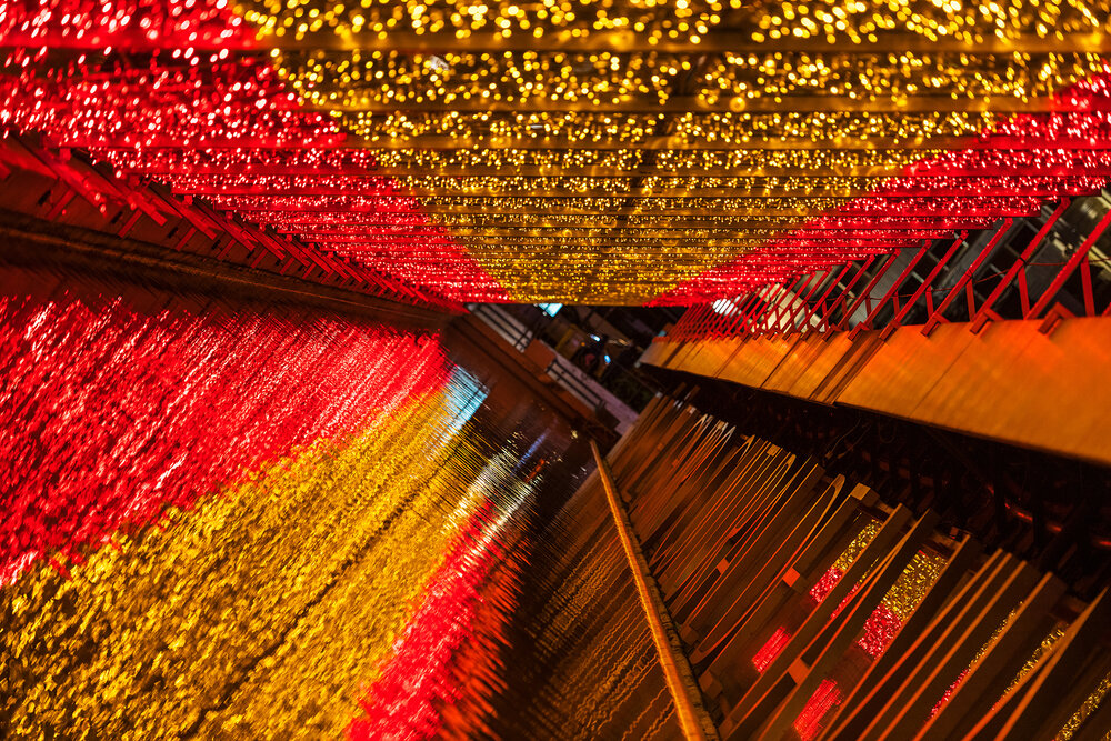 Detail and reflection of the Christmas decorations in Plaza de Colon in Madrid, with the entrance to the theatre covered with a Spanish flag made of lights
