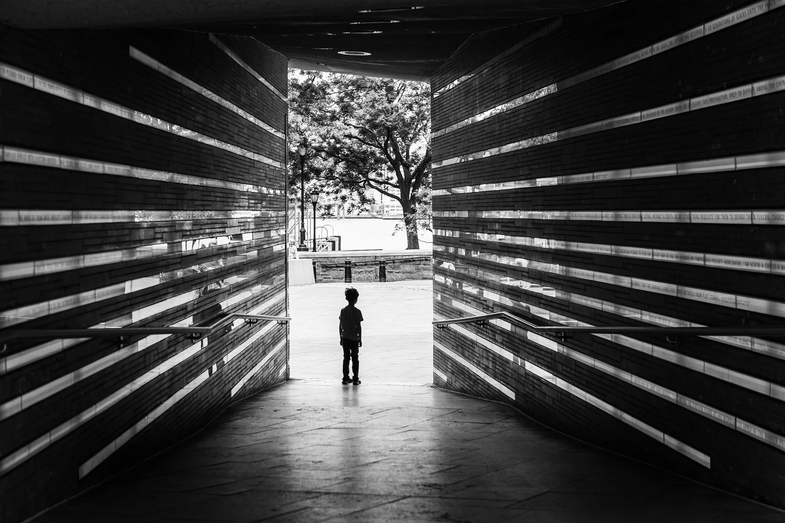 Young boy at the entrance to the illuminated passageway in the Irish Hunger Memorial in Lower Manhattan, New York City.