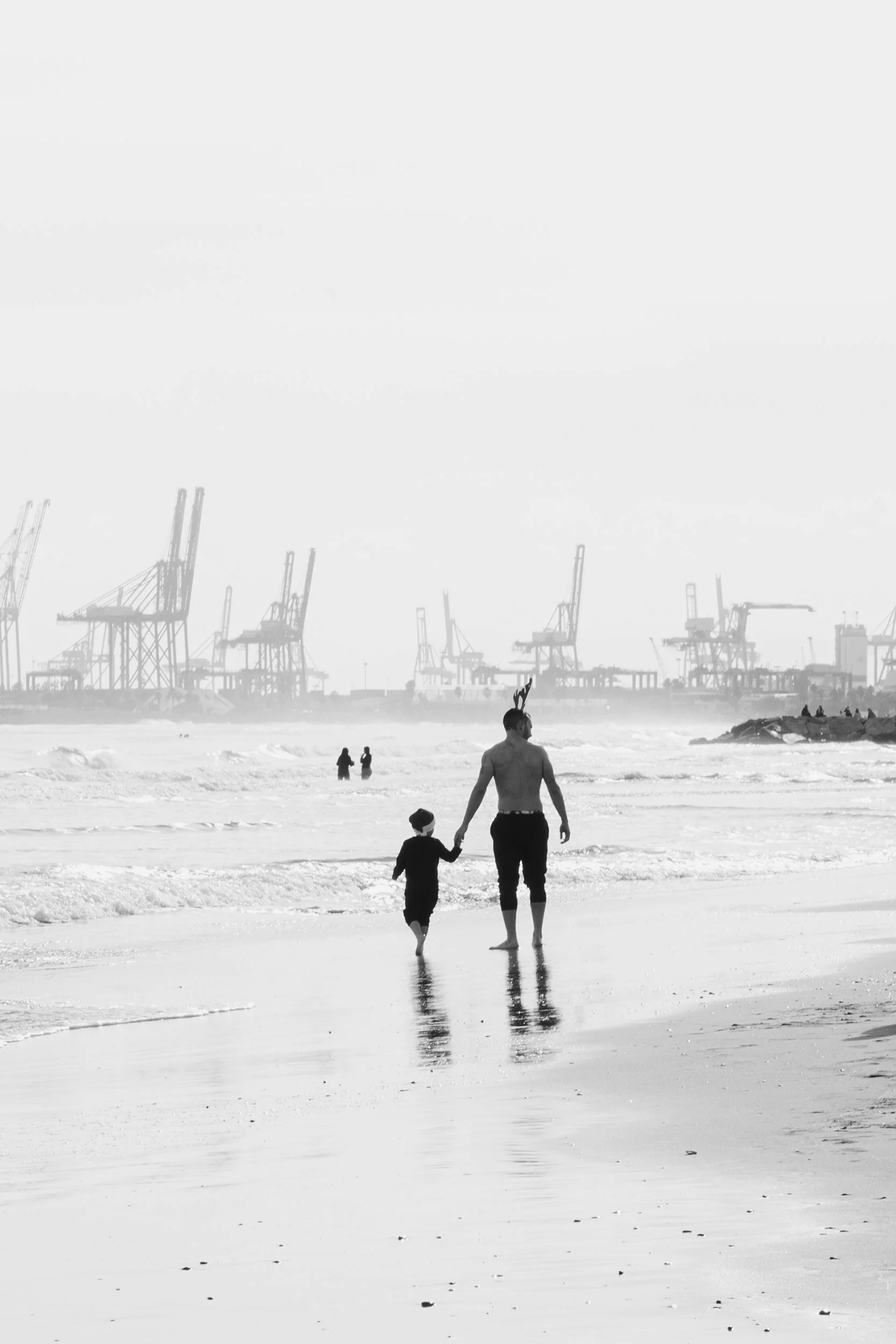 A father and son walk hand in hand along the shore on New Year’s Day in Valencia