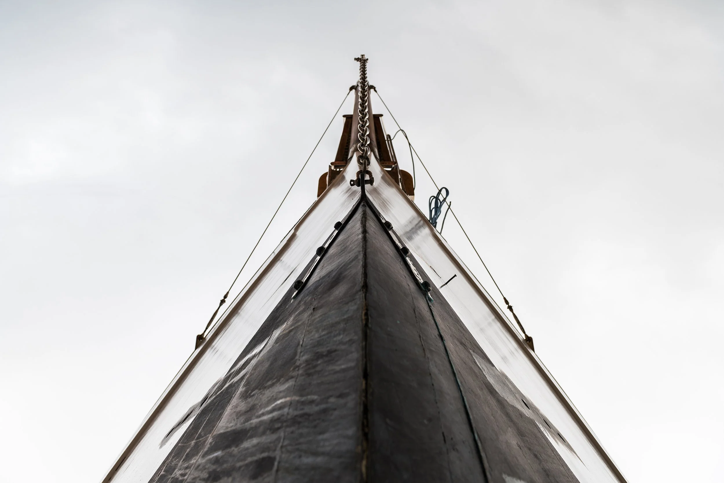 Low angle-view of the bow of a wooden luxury sail boat against a cloudy sky.