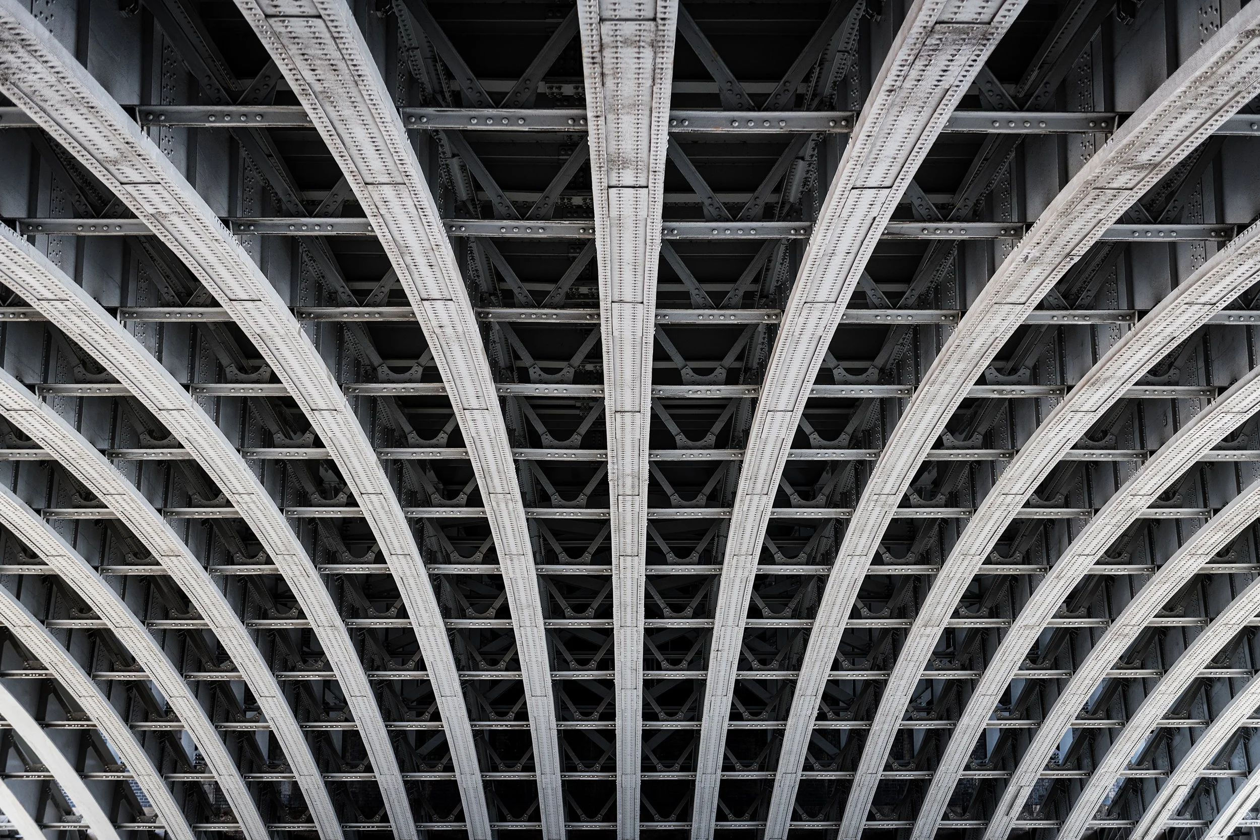 Symmetric steel framework under a bridge over the river Thames in London.