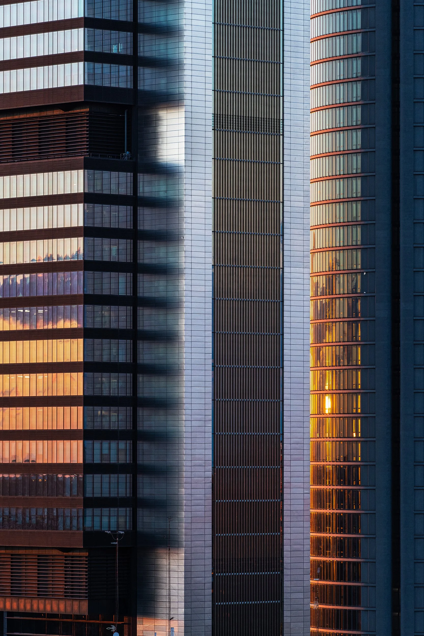Close-up view of the textured façades of modern skyscrapers in Madrid at dusk. 