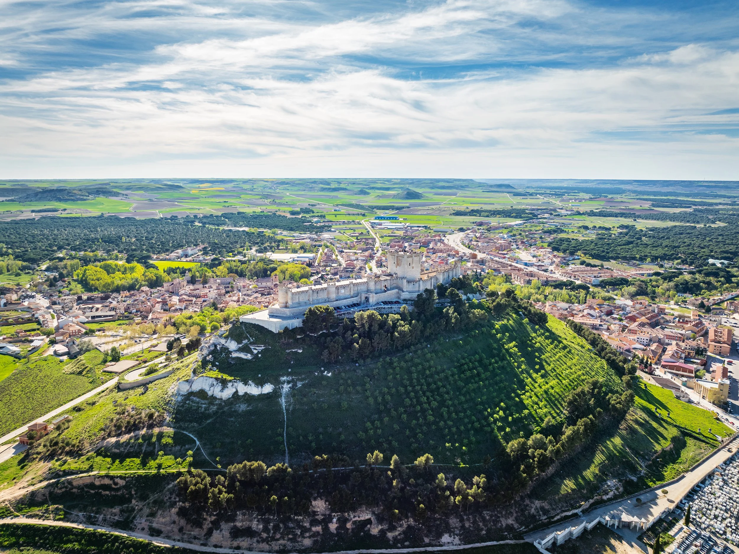 Aerial view of the famous castle of Peñafiel in Valladolid at dusk, with the old village and wine cellars in the background.